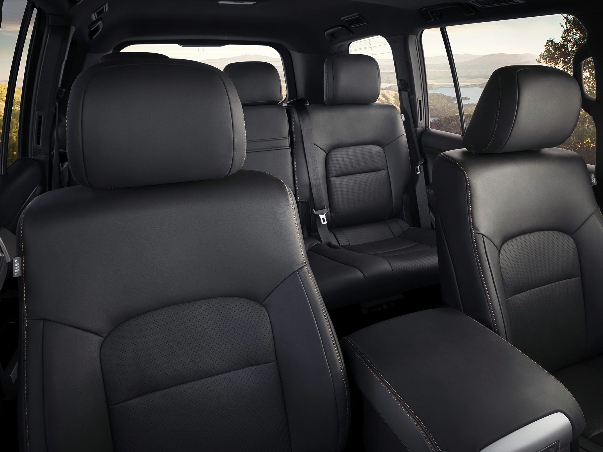Black leather multi-row seating with detailed stitching and spacious cabin