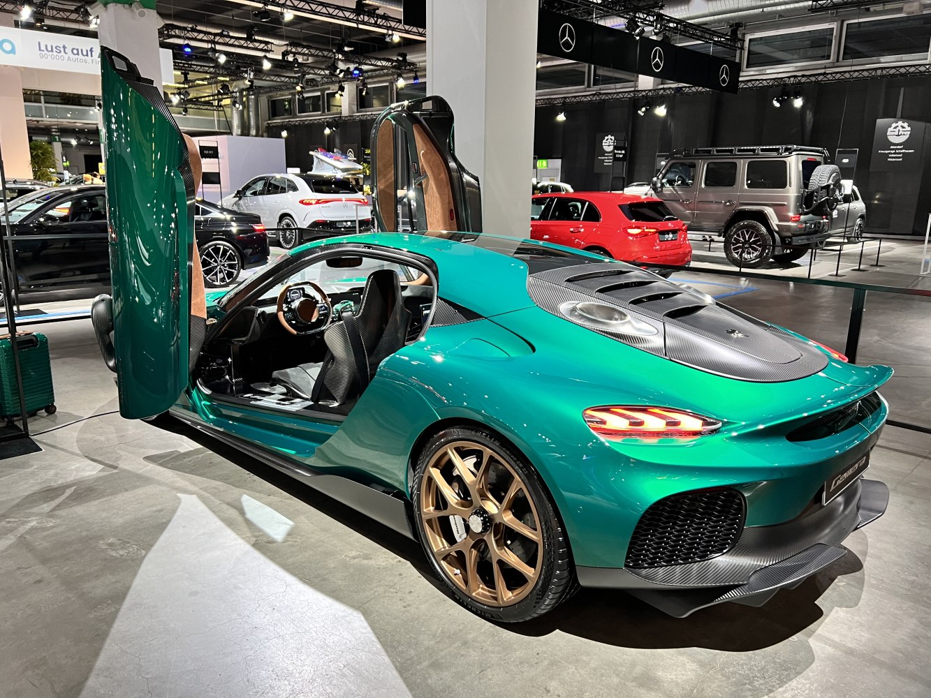 Green sports car with open butterfly doors and bronze alloy wheels