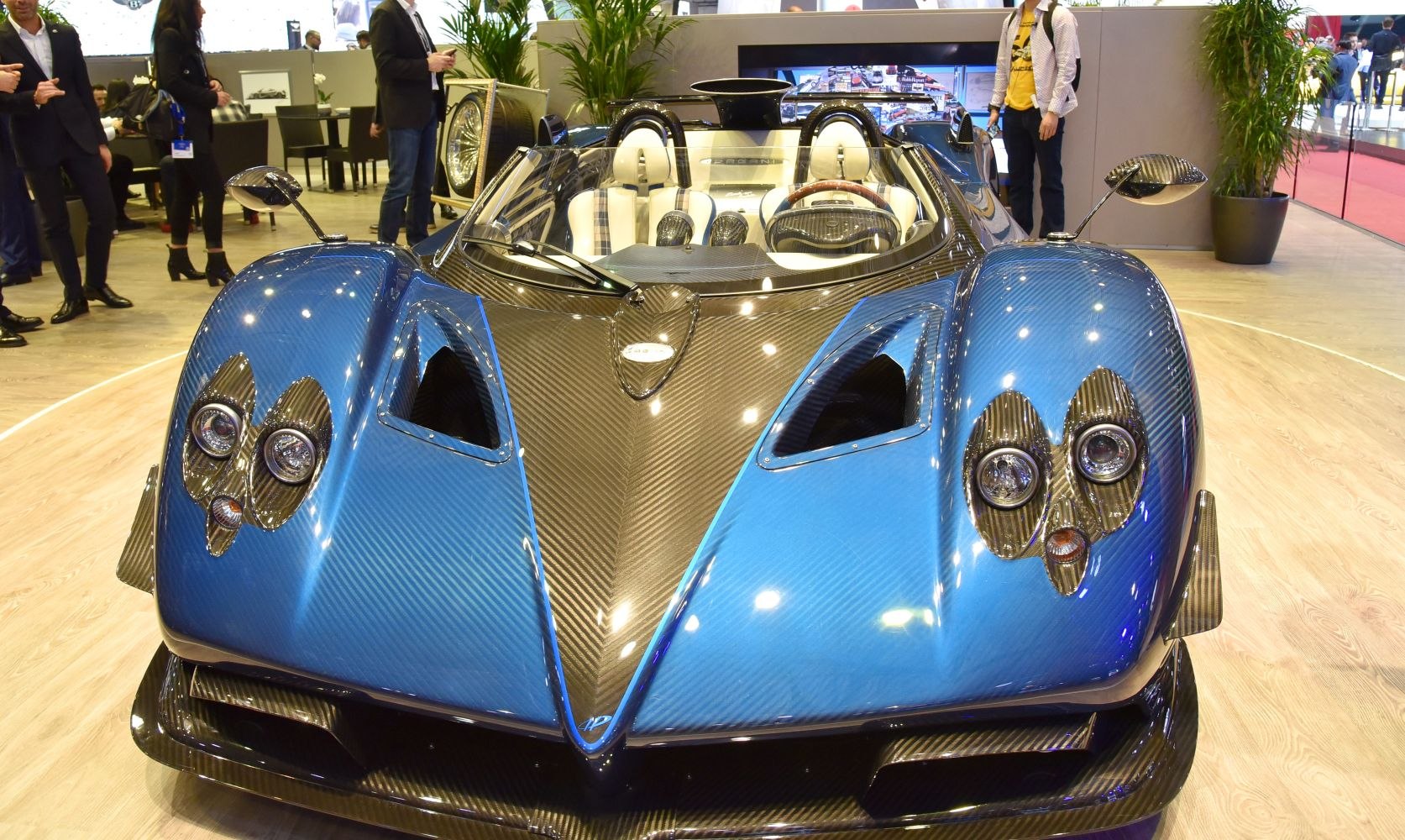 Front view of blue carbon fiber supercar with twin headlights and aerodynamic shape