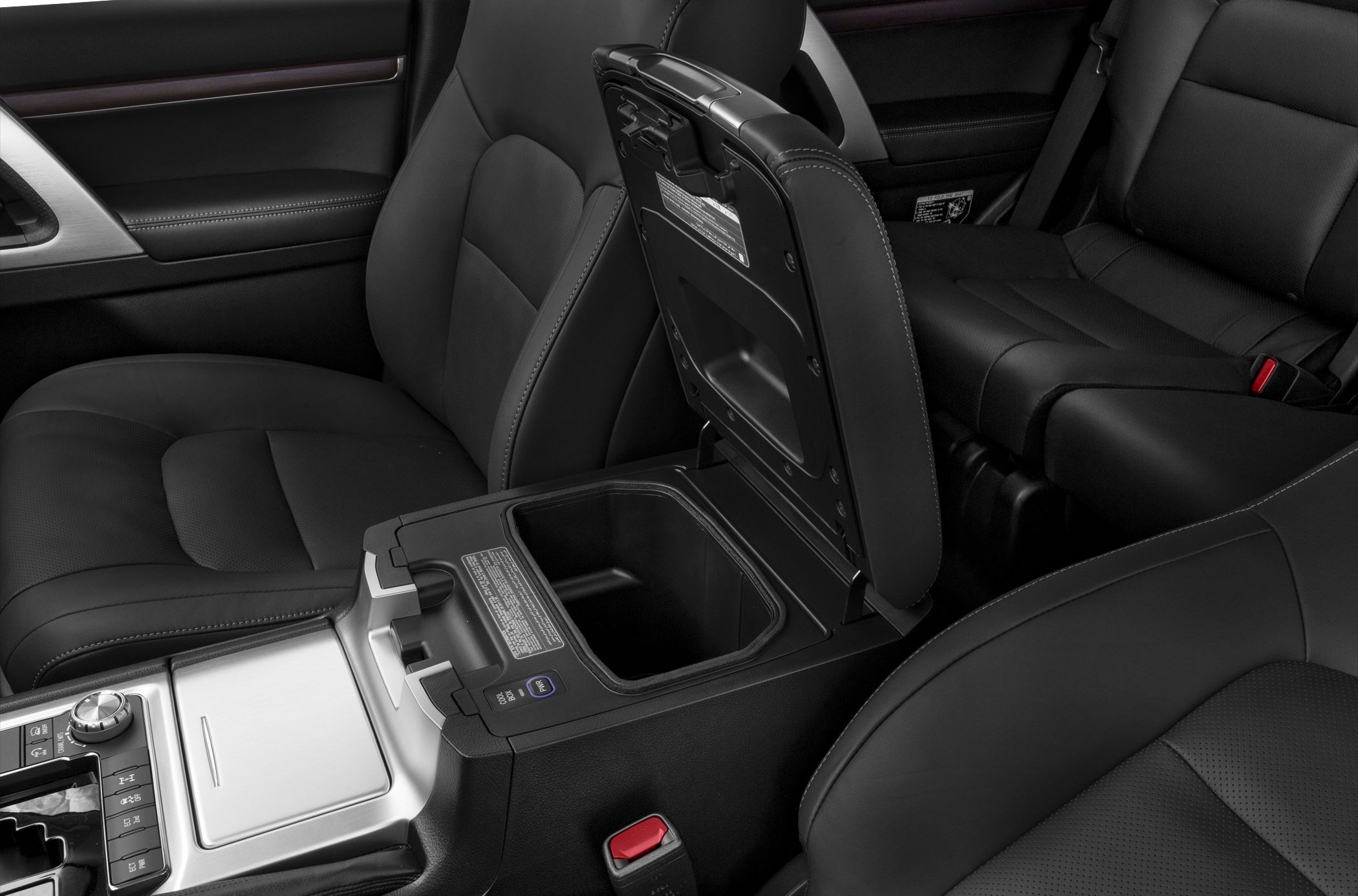 Open center console storage and black leather seats inside vehicle interior.