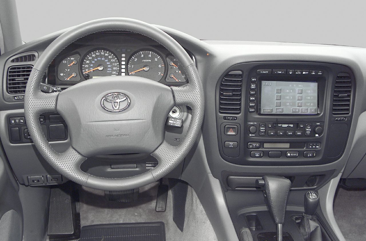 Steering wheel and dashboard of a vehicle interior with control panel and instrumentation.