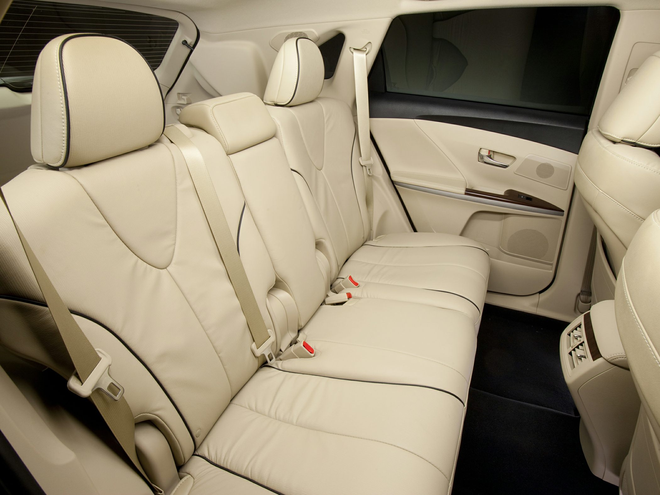 Beige leather rear seat and door panel with seat belts in car interior