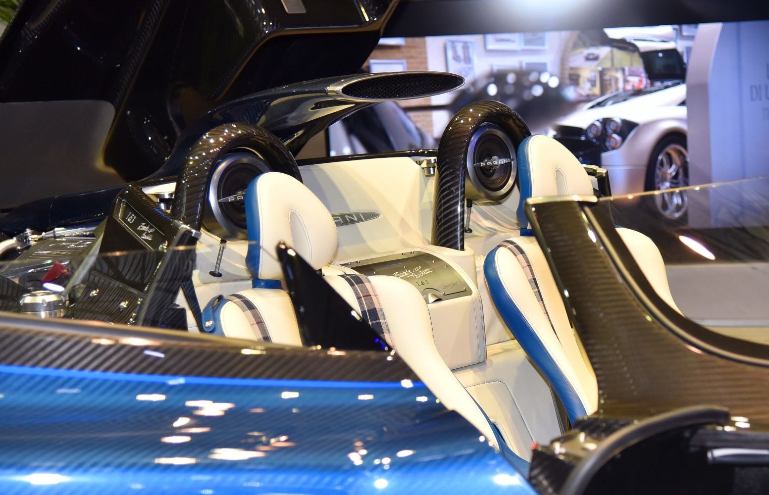 Luxurious white-blue leather seats with carbon fiber roll hoops in supercar interior.