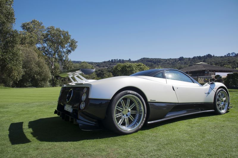 Rear and side view of a supercar with a large aero wing and carbon fiber lower body.