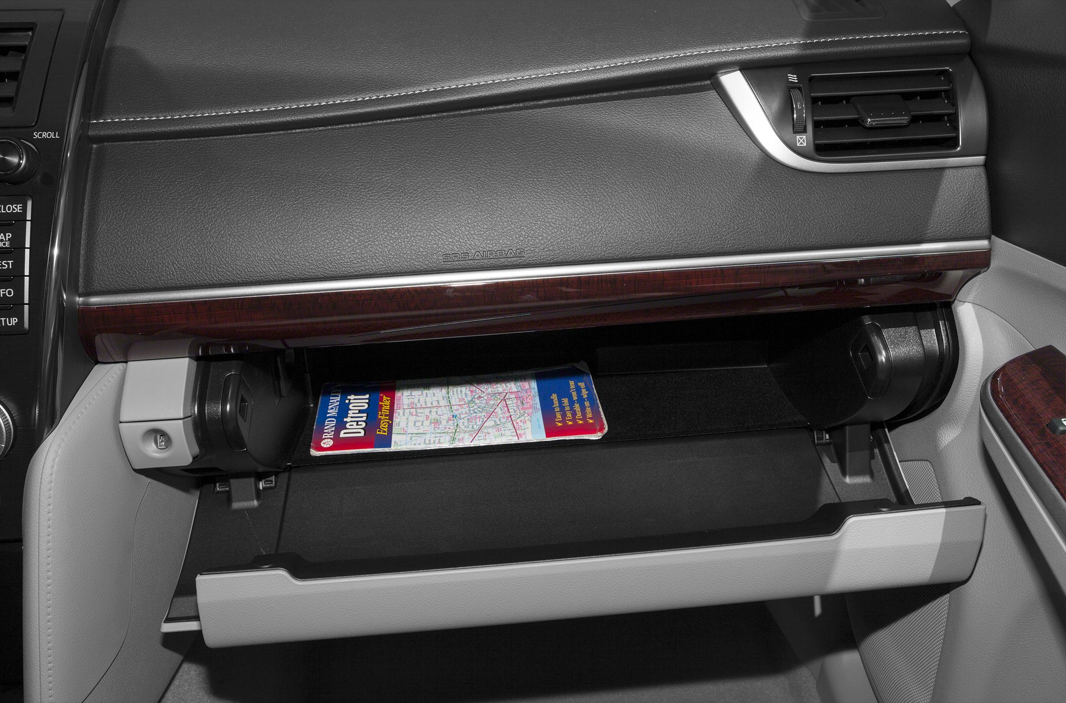 Open glove compartment with map inside, dashboard air vent and trim
