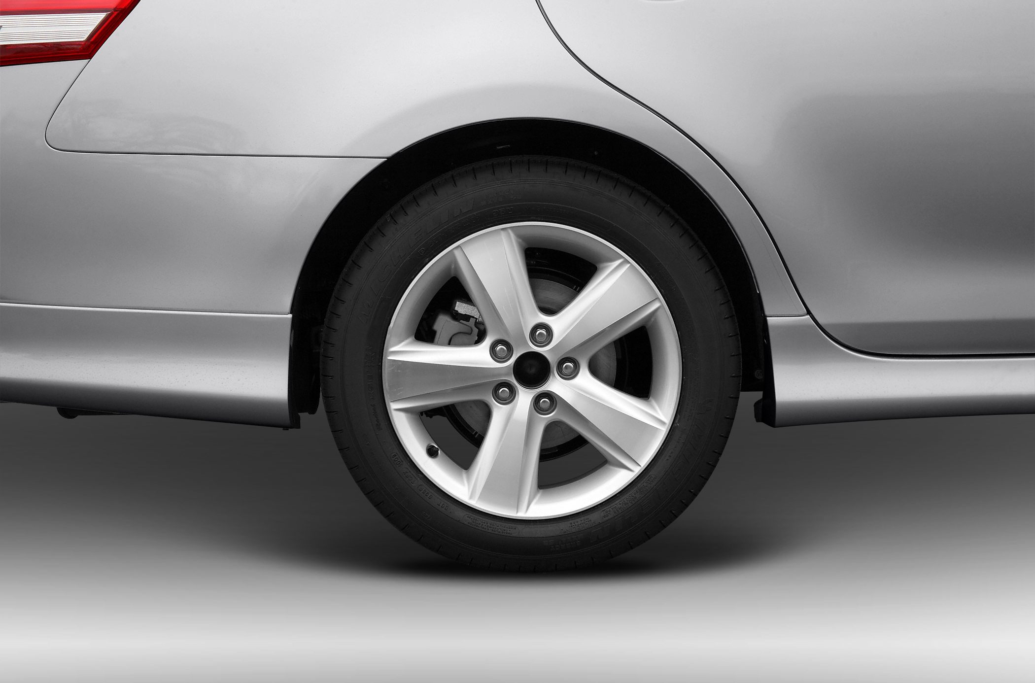 Rear alloy wheel with brake disc and tire on silver car body