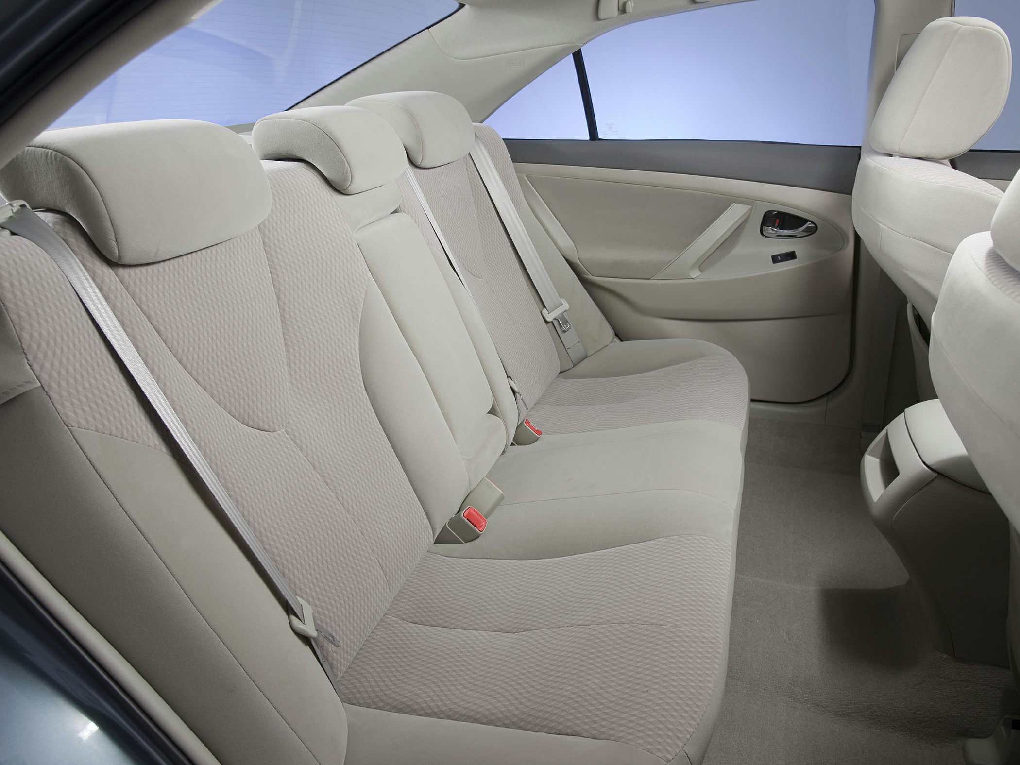 Rear seat with beige fabric upholstery, headrests, and seat belts