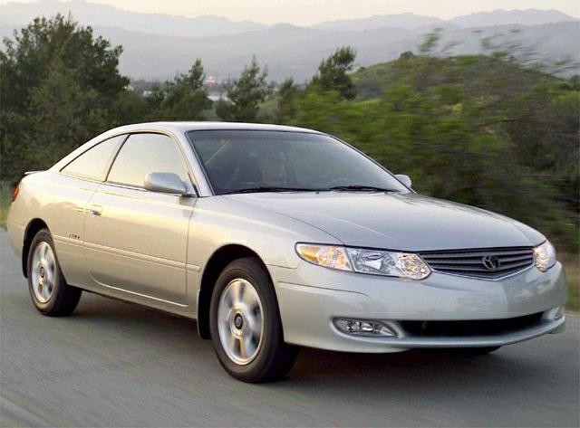 Front side view of silver compact coupe driving on road
