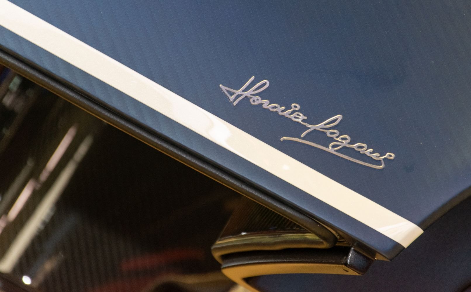 Close-up of Horacio Pagani signature emblem on a racing stripe roof section