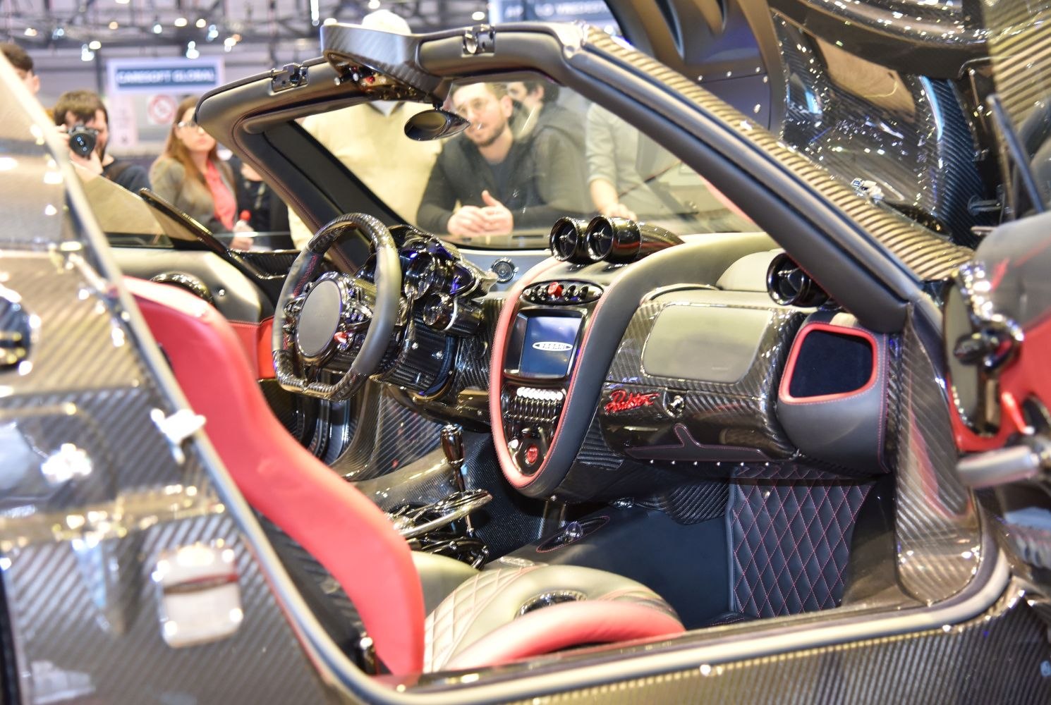 Carbon fiber luxury sports car interior with red leather seats and detailed dashboard.