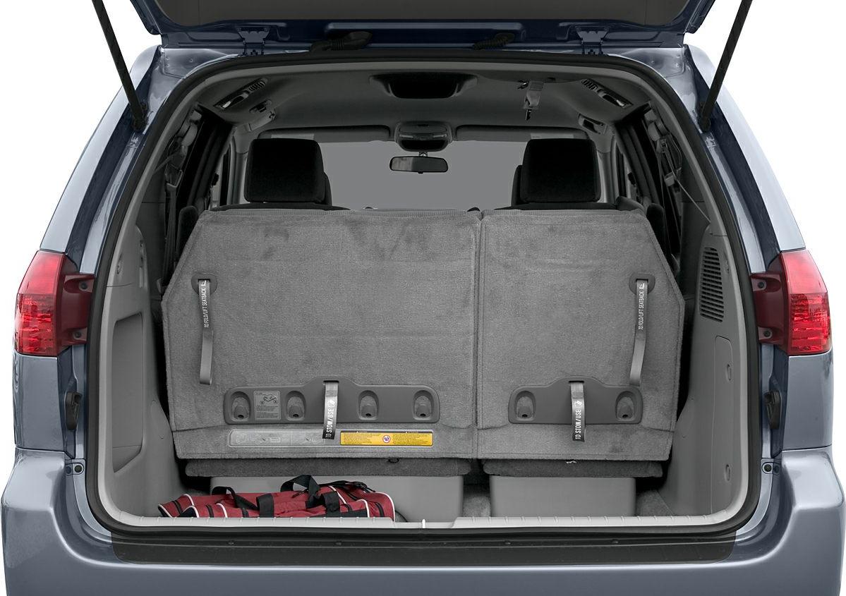 Minivan rear cargo with folded third-row seats and storage space.