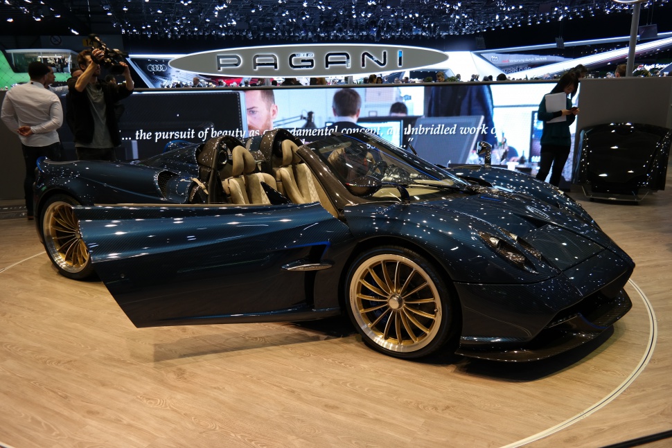 Open-top carbon fiber luxury supercar with gold alloy wheels and beige interior.