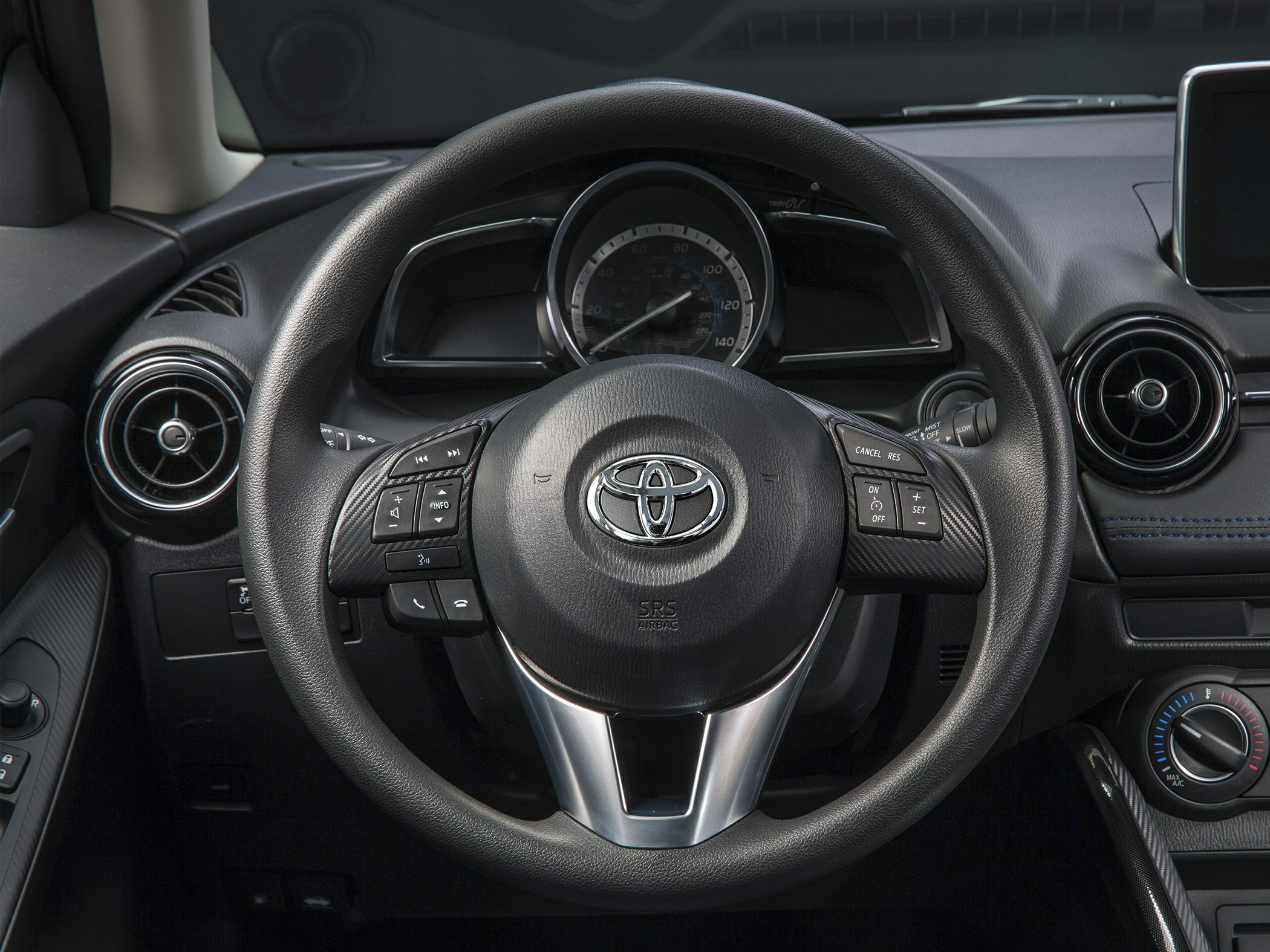 Steering wheel with integrated controls and round air vents on car dashboard