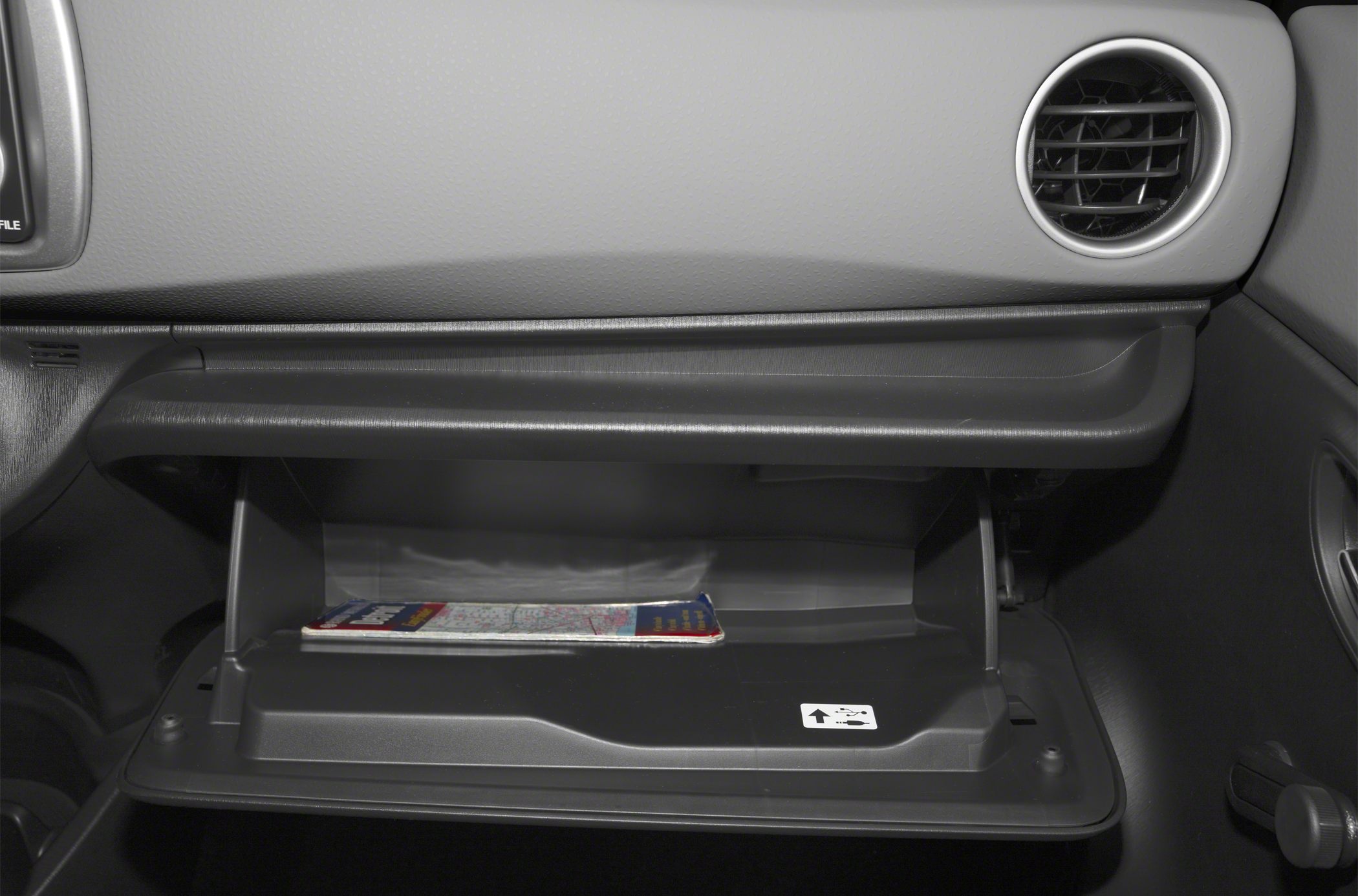 Open glove compartment with a map inside and air vent nearby