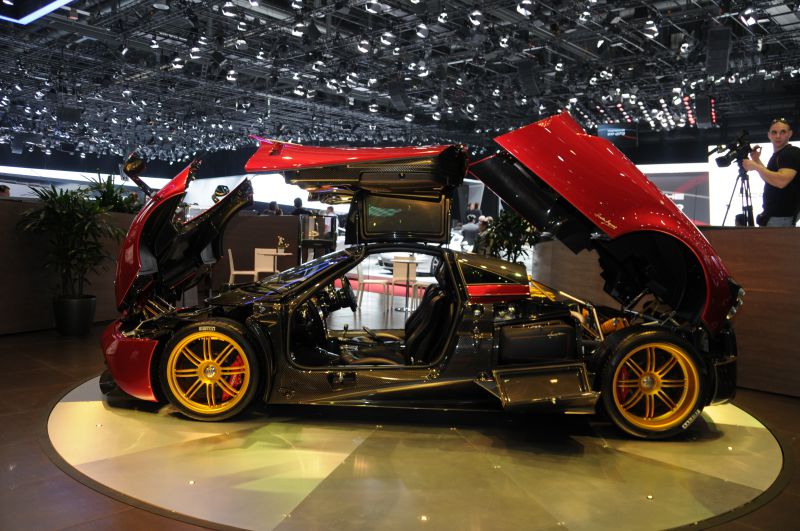 Side view with open gullwing doors and front hood, golden rims visible.