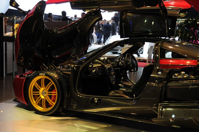 Open gullwing doors, carbon fiber body, visible car interior with luxury and tech details