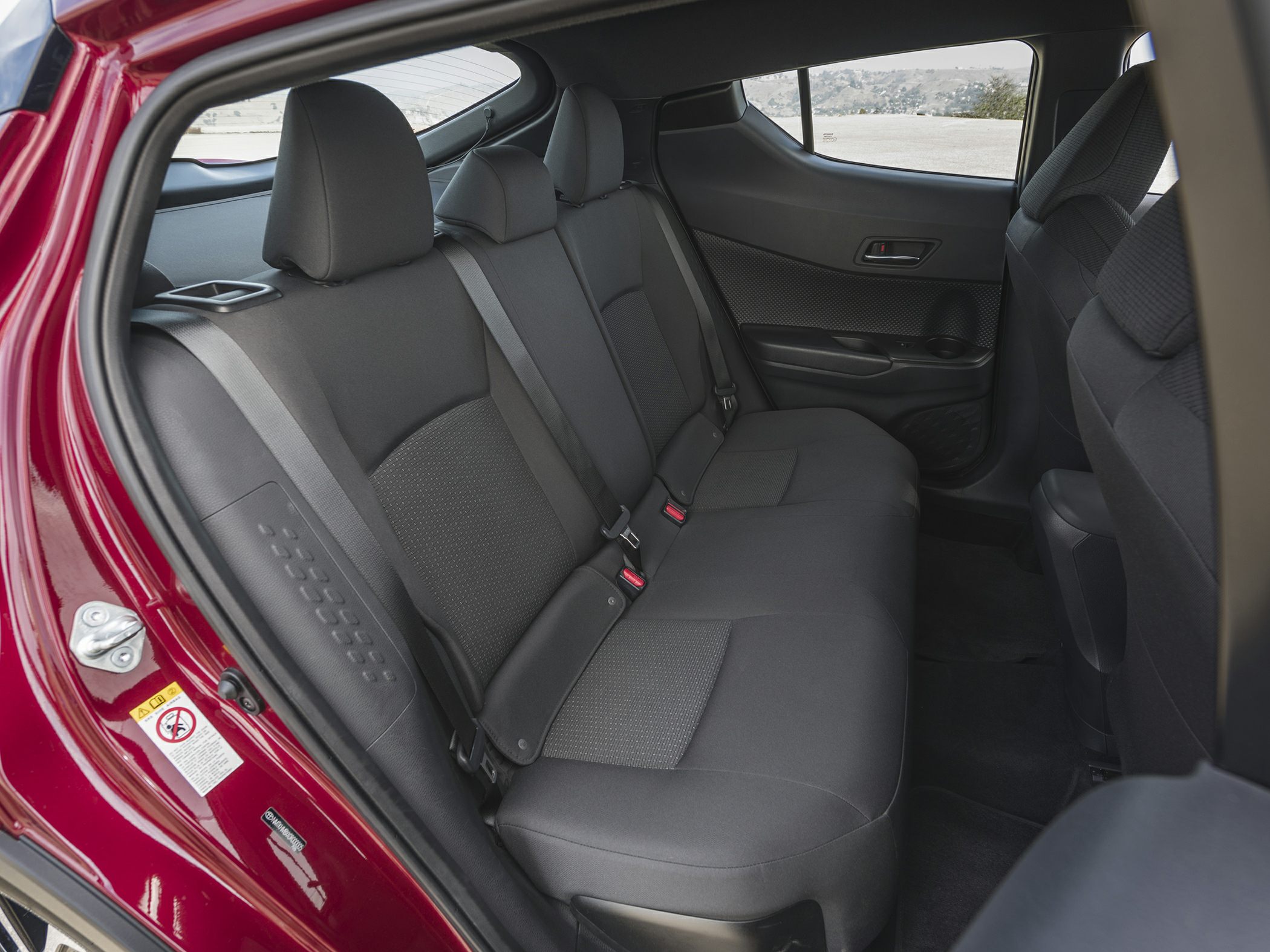 Rear seating area with fabric upholstery, seat belts, and door panel.