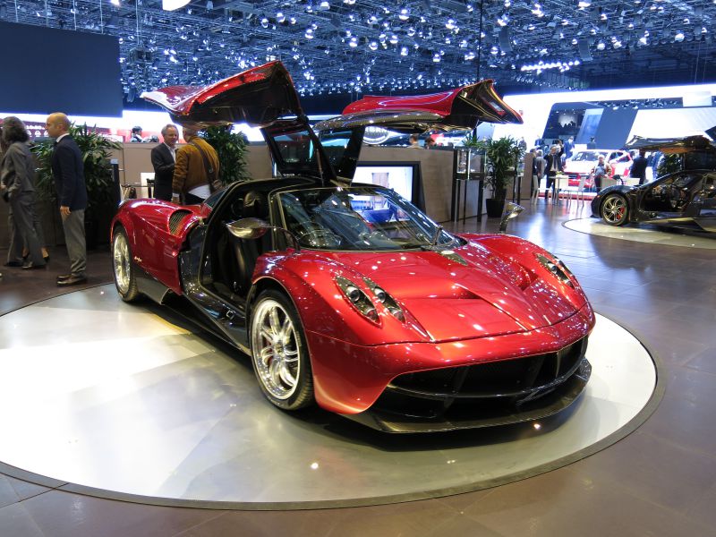 Sleek red supercar with gullwing doors and aerodynamic body design.