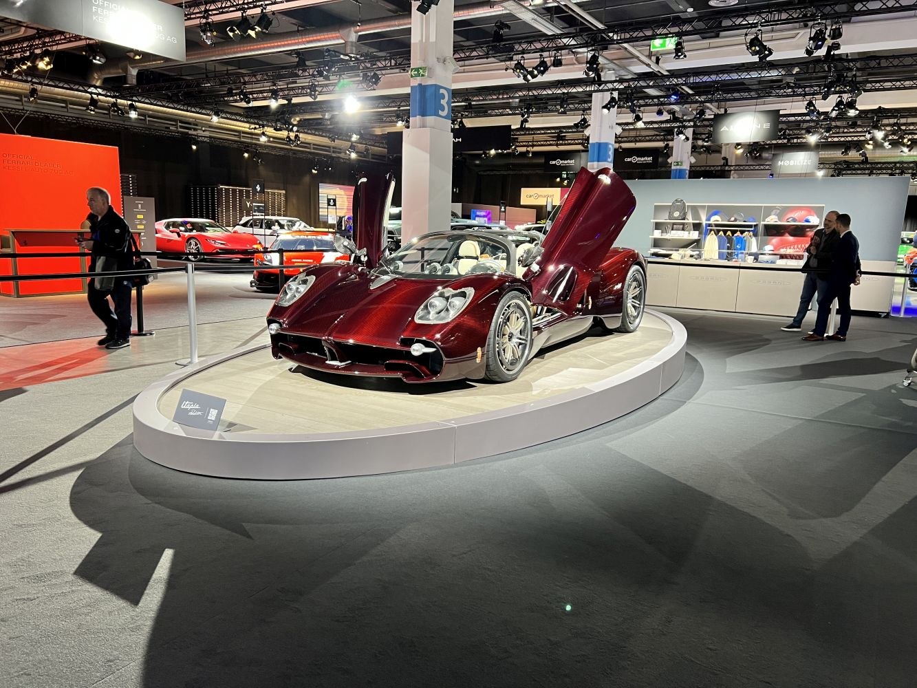 Luxury roadster with open butterfly doors on round display platform