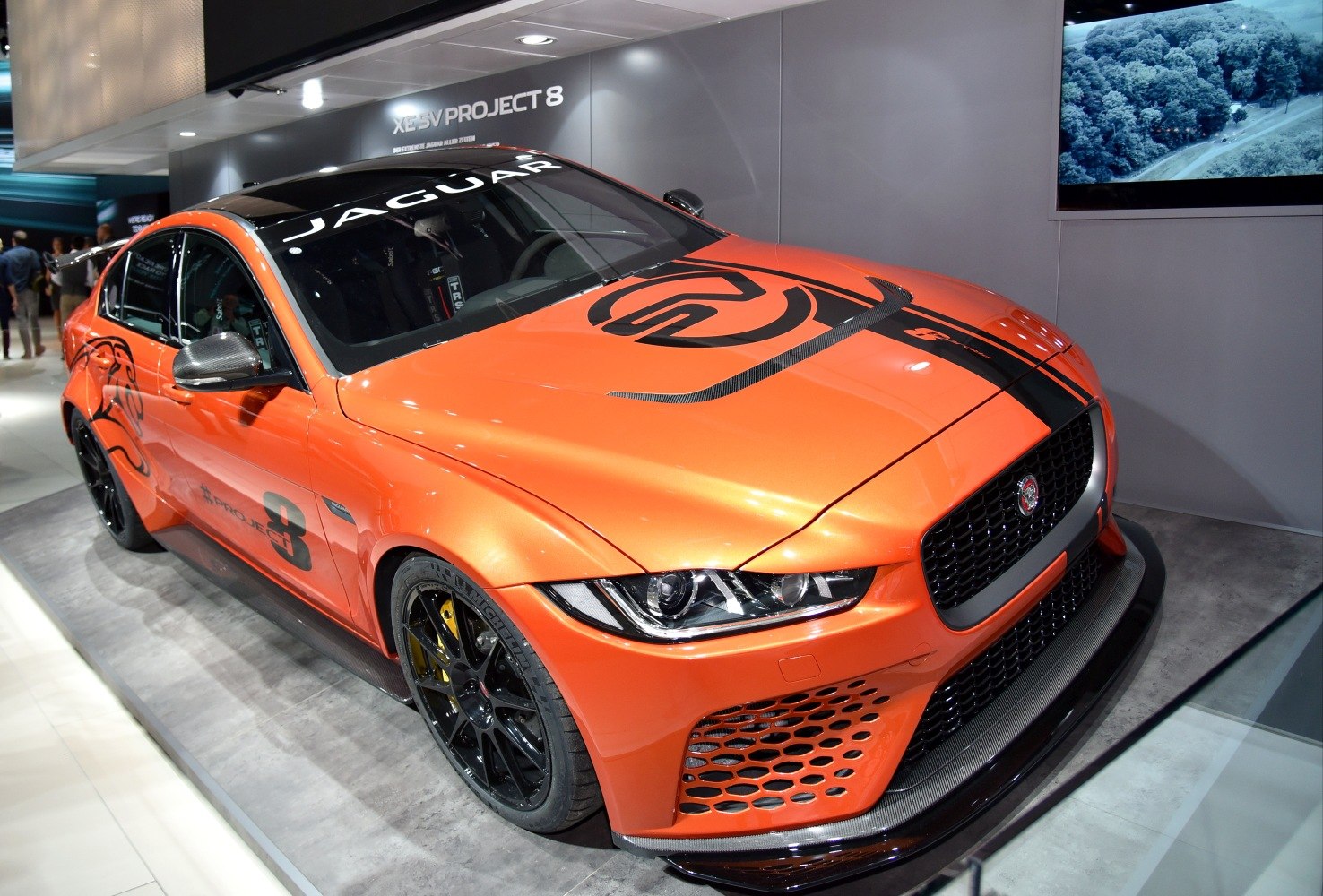 Orange racing sedan with aerodynamic front and black wheels