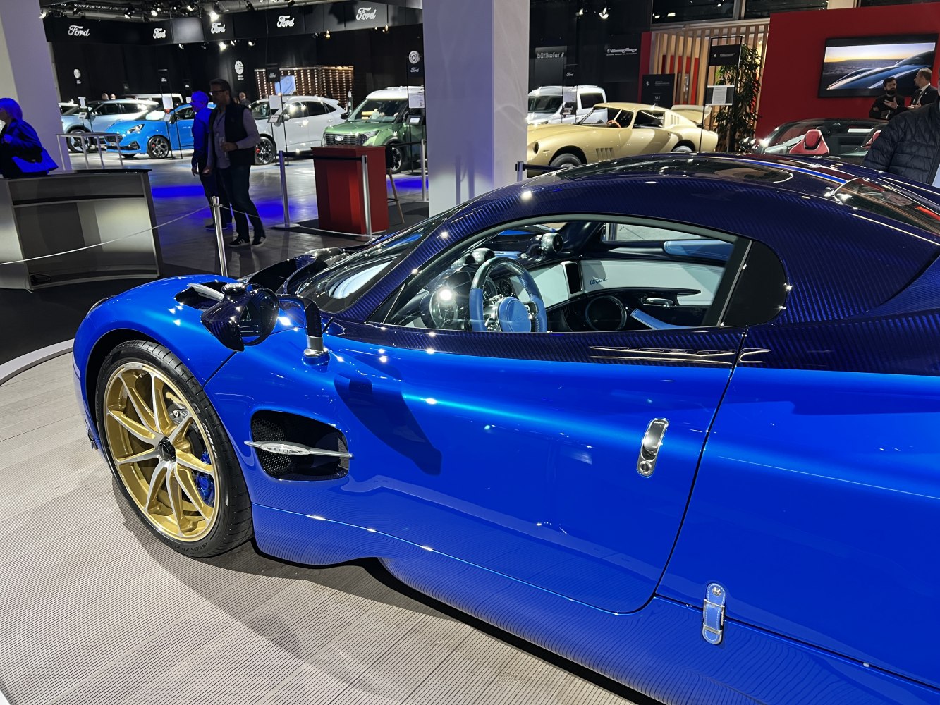 Blue hypercar side profile with gold wheels and carbon fiber details
