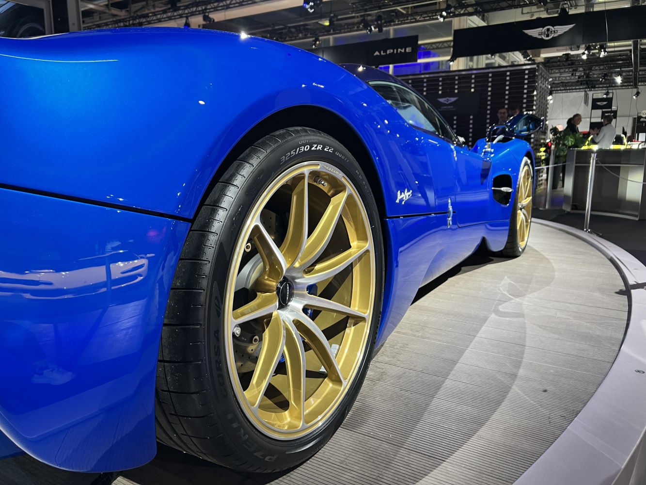 Blue supercar rear with gold multi-spoke wheel and wide tire