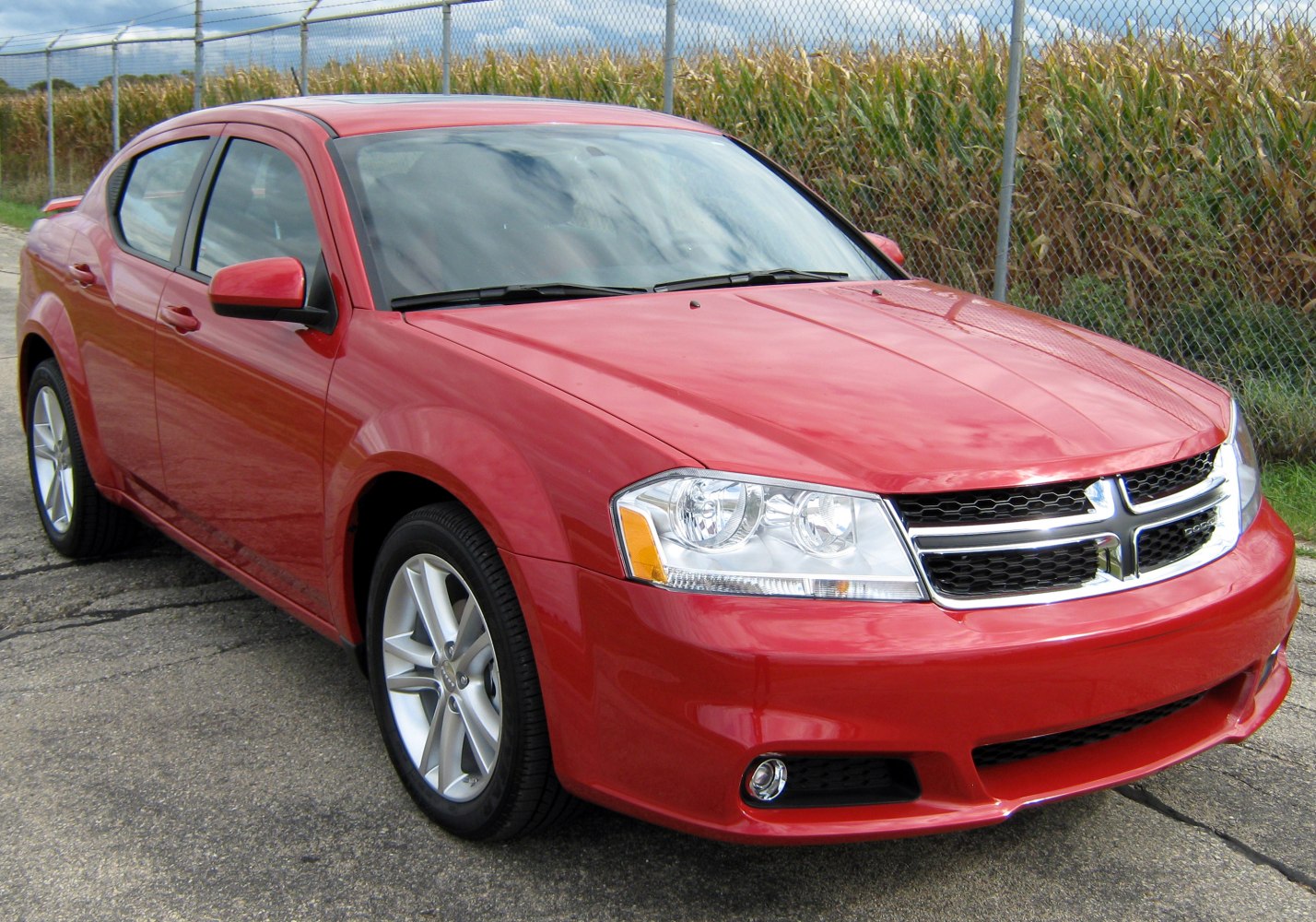 Red sedan with chrome grille and clear multi-lens headlights.