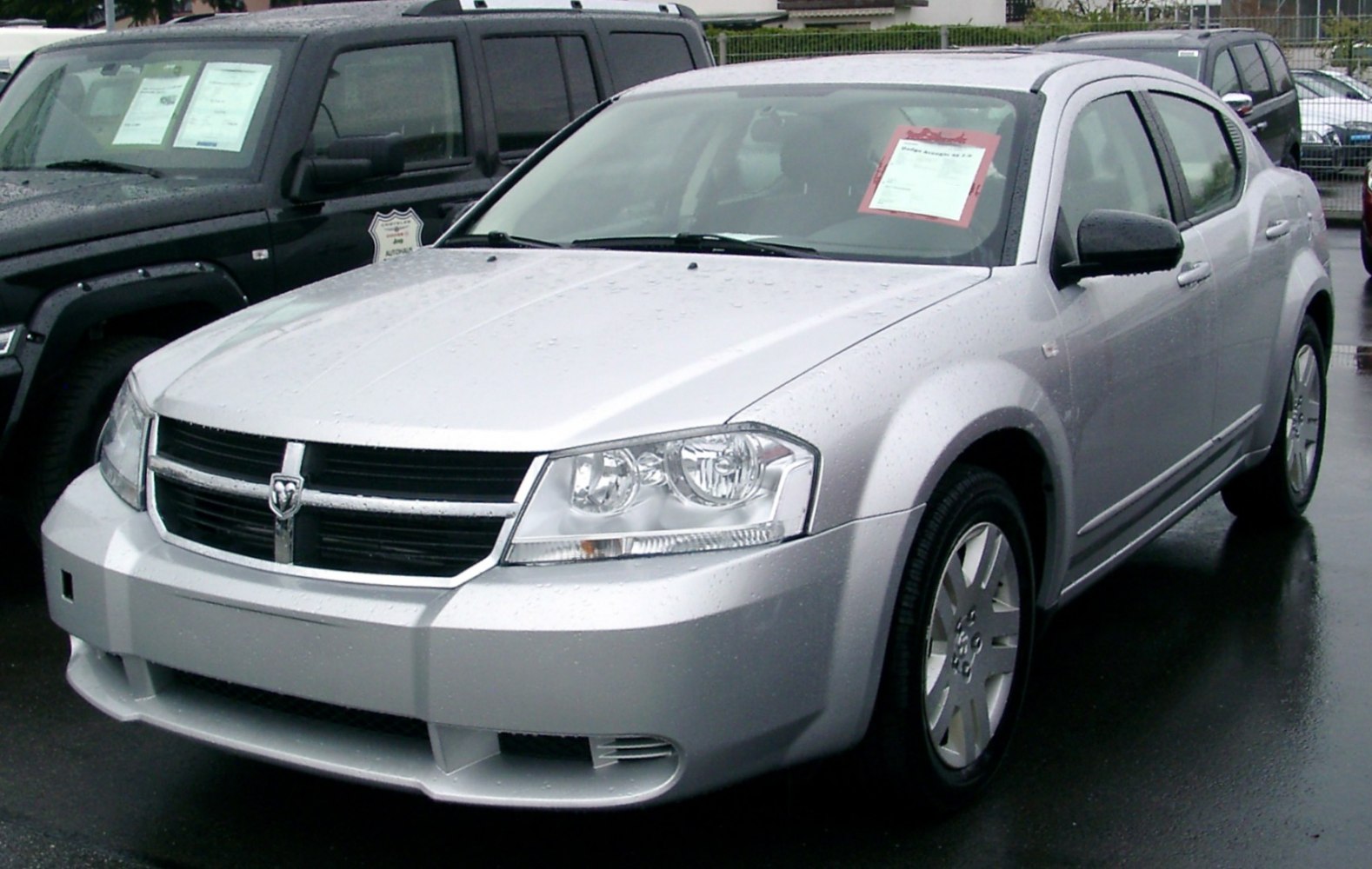 Silver sedan showcasing front grille, headlights, and side profile on wet pavement
