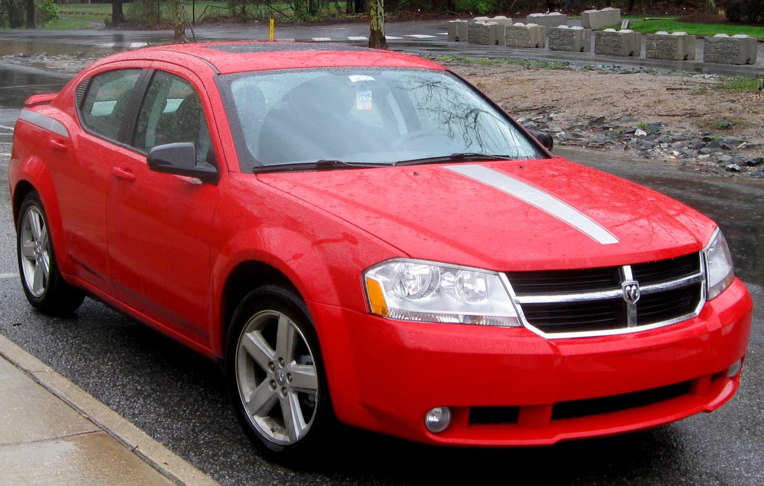 Red sedan with racing stripe, alloy wheels on wet pavement