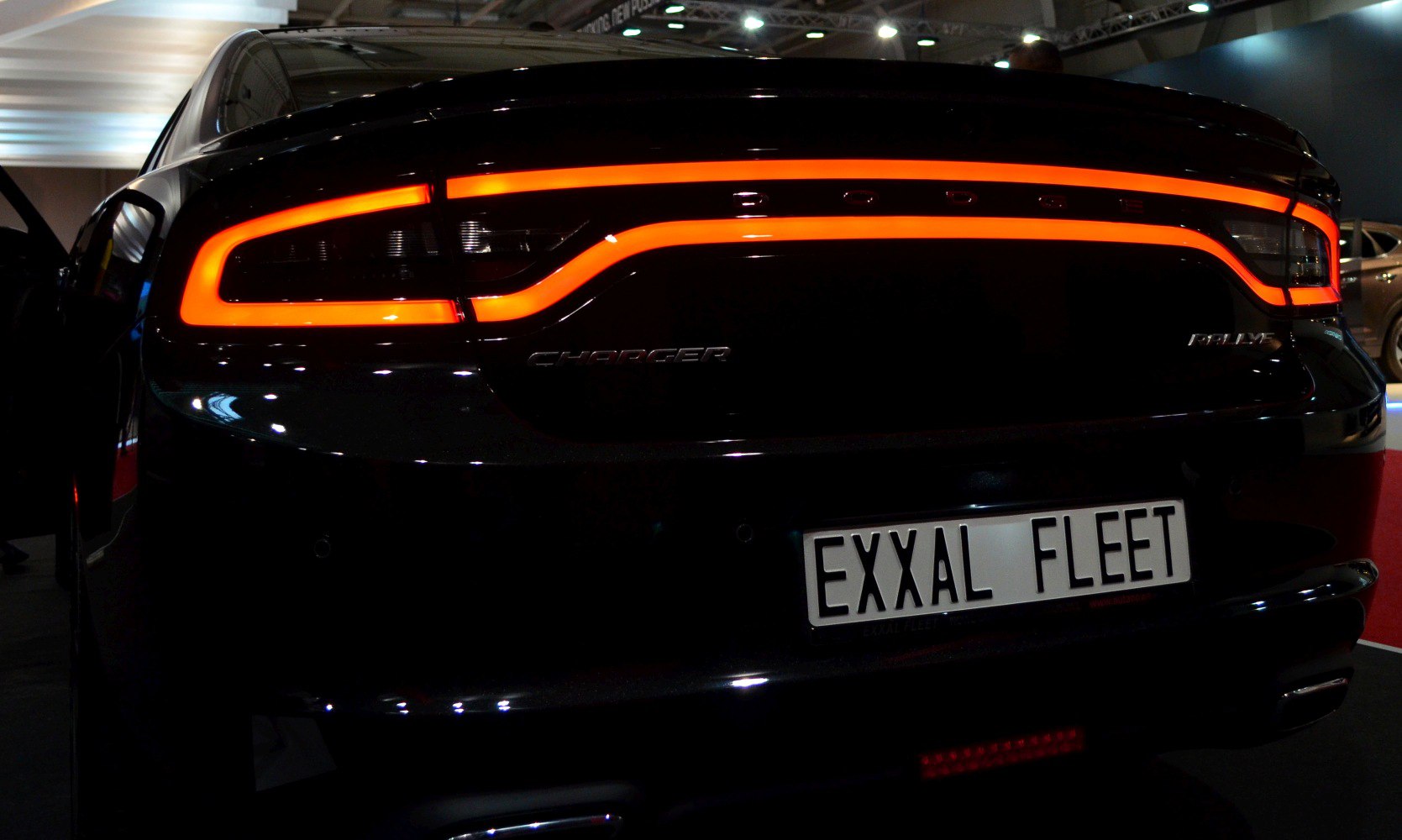 Illuminated rear taillights with Dodge and Charger emblems on a black vehicle.
