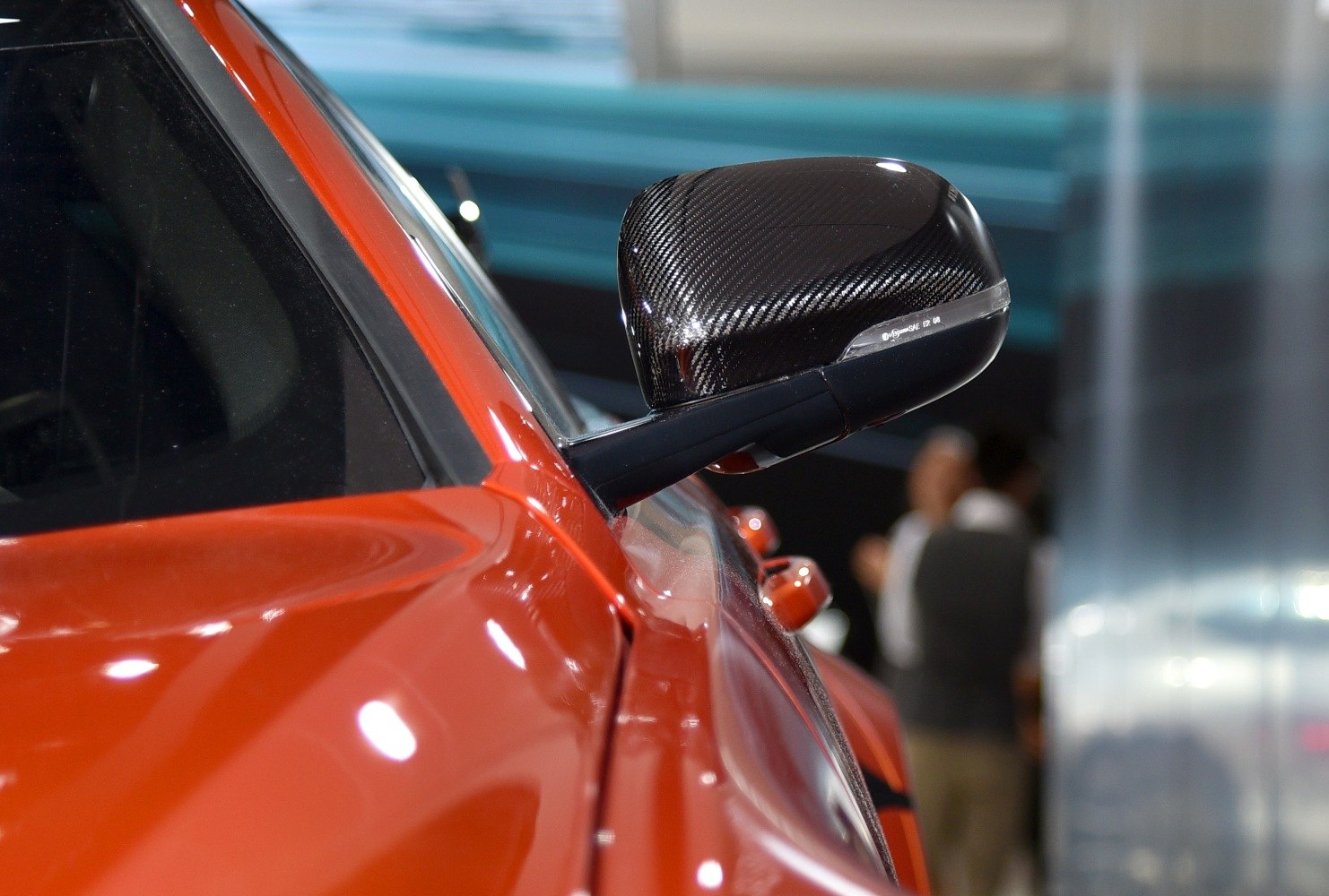 Carbon fiber textured side mirror on red vehicle door.