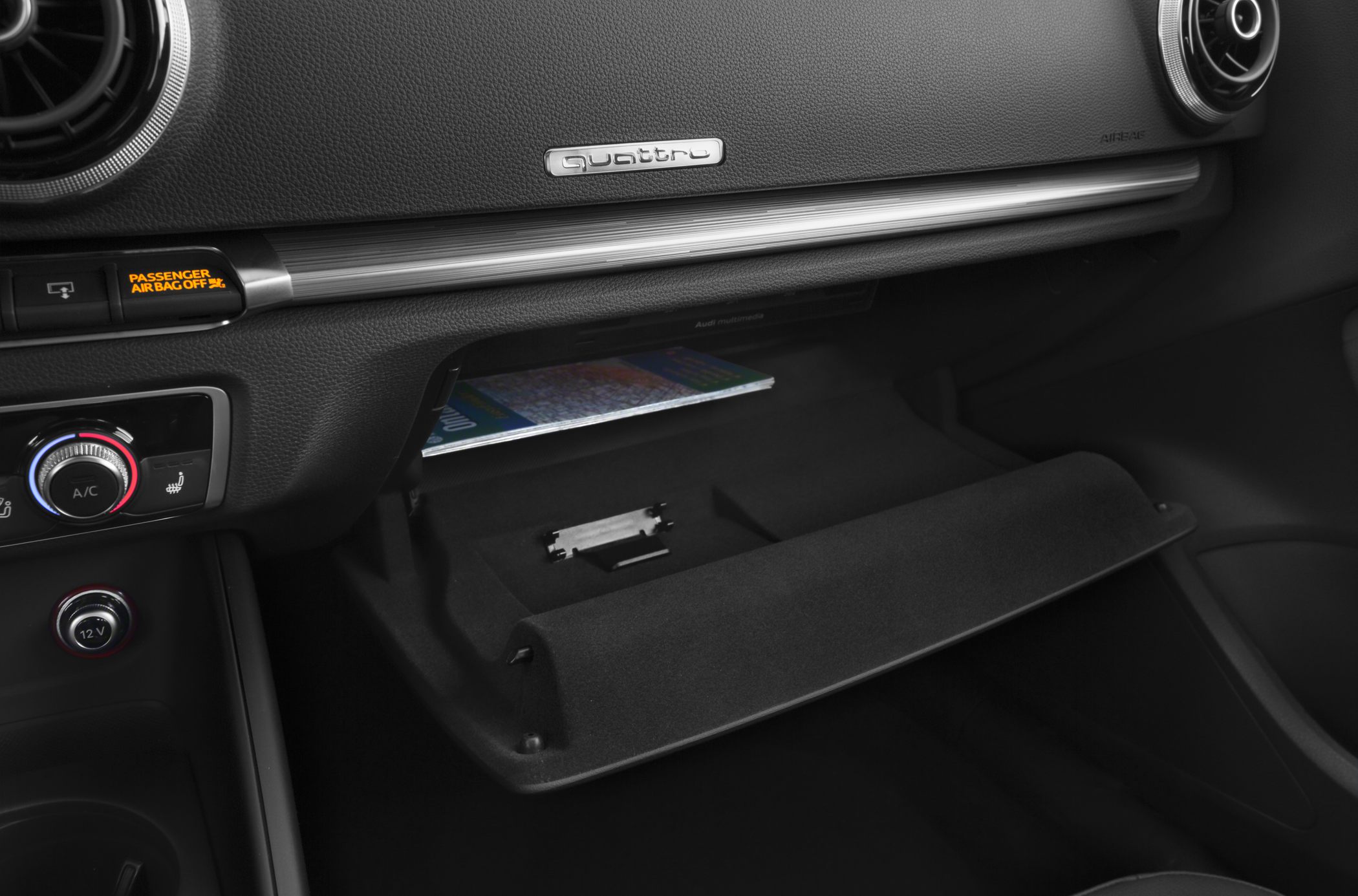 Open glove compartment and quattro badge on car dashboard