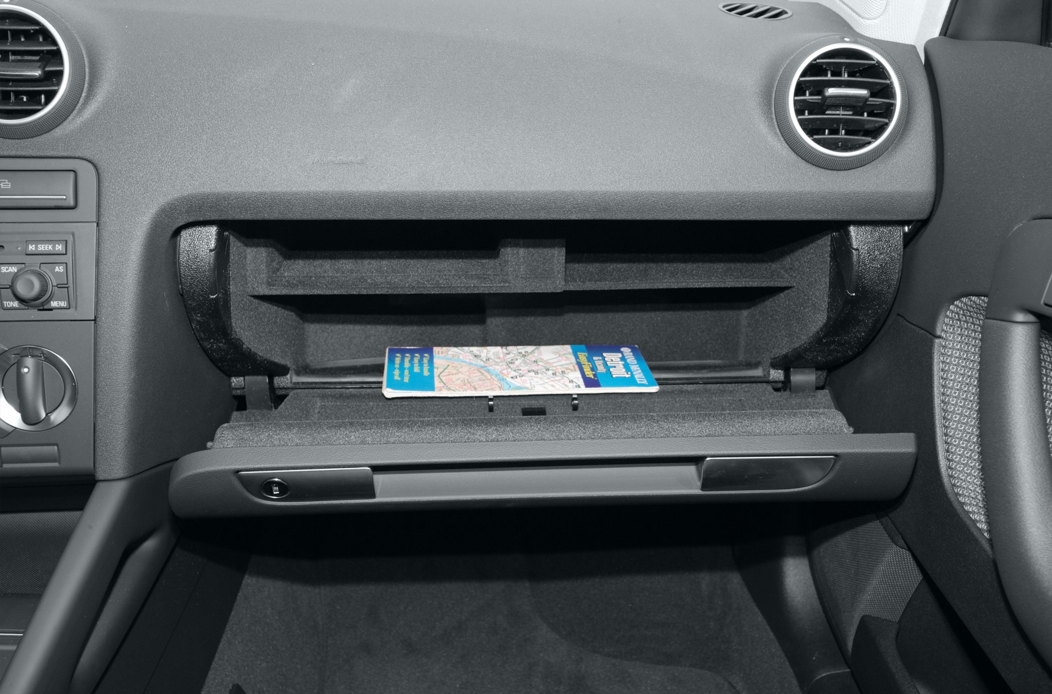Glovebox with a map inside, dashboard section, and air vents.