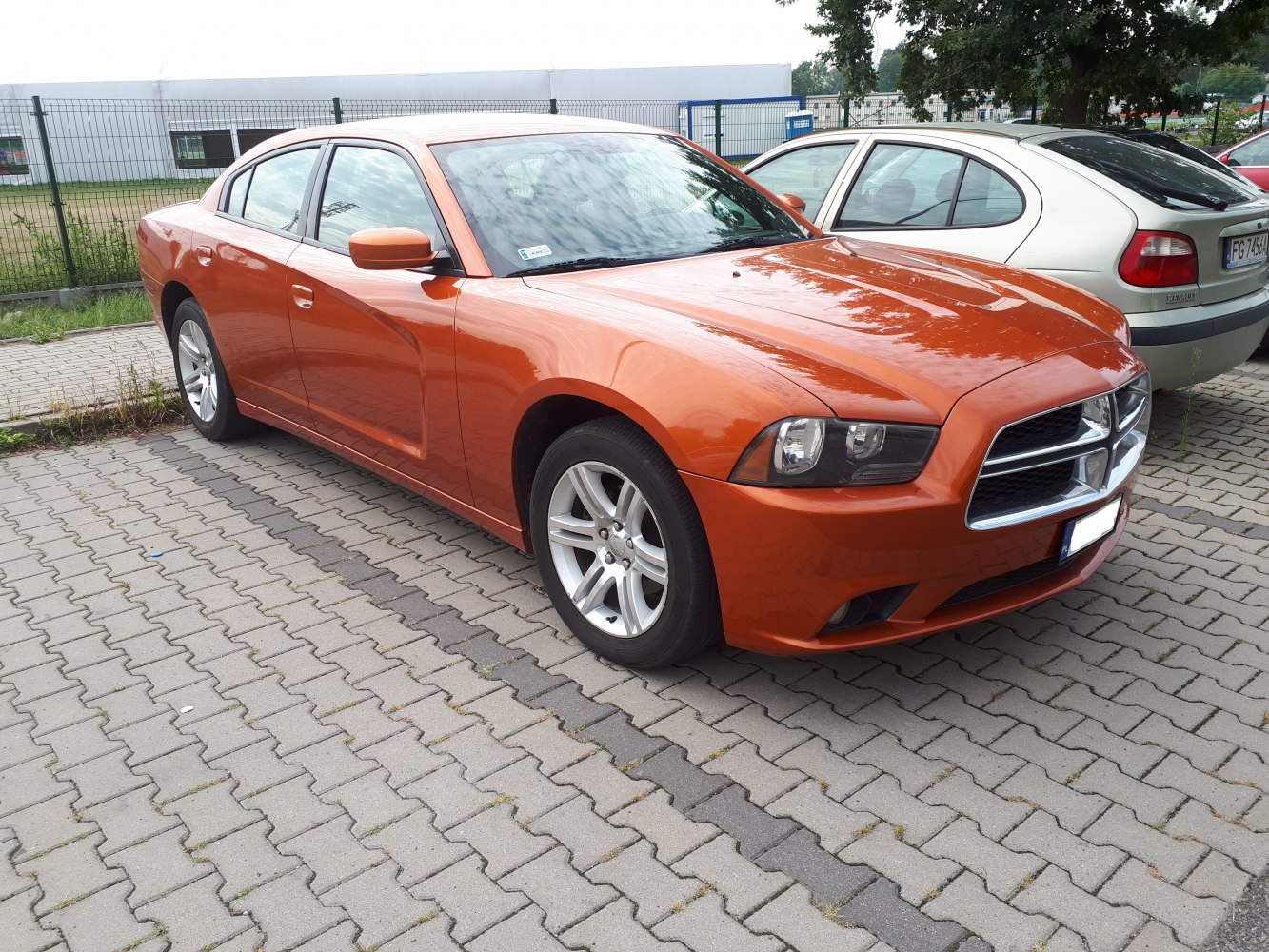 Orange sedan front and side view with headlights and alloy wheels