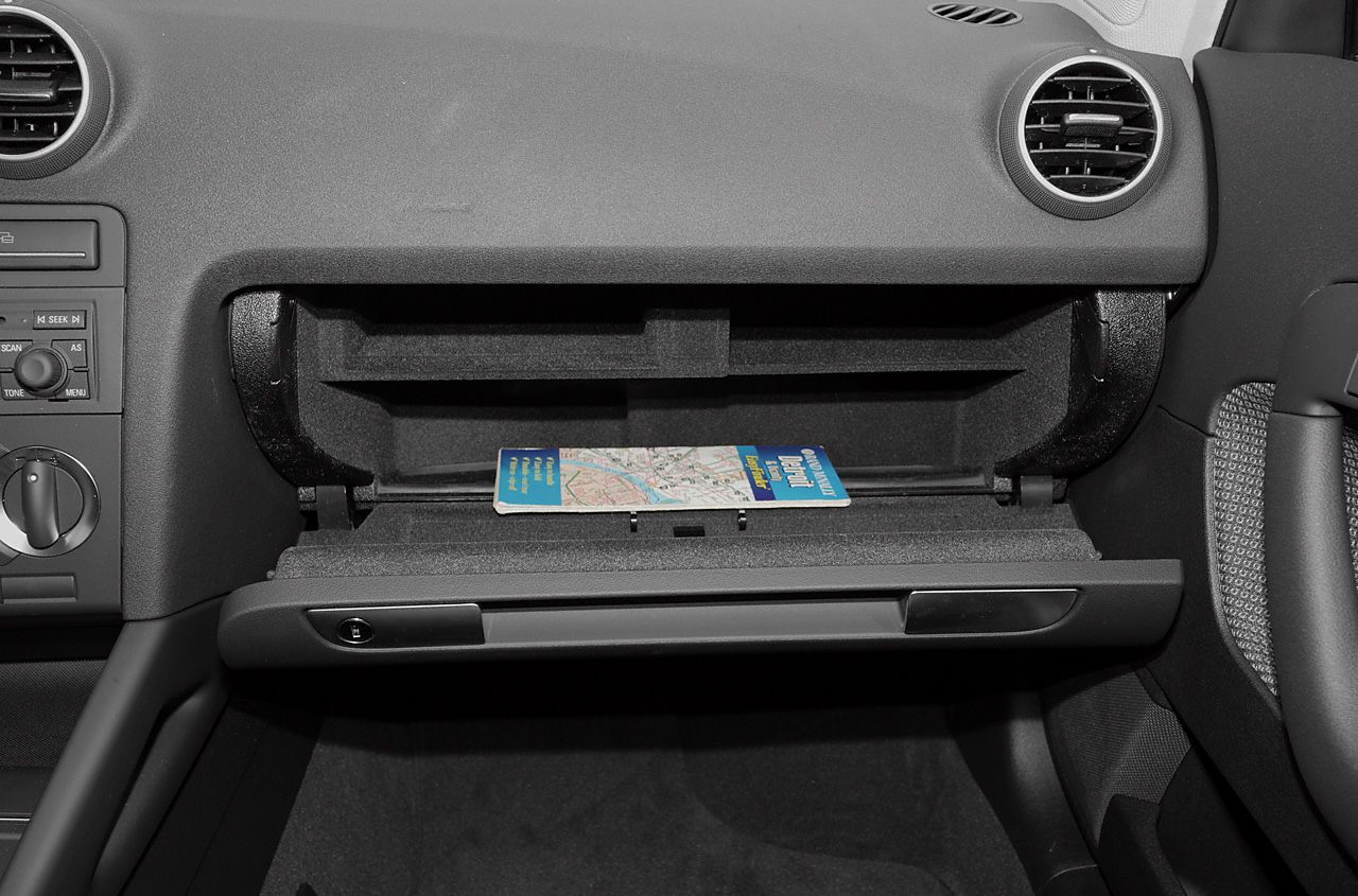 Open glove compartment with map inside, dashboard air vents visible.