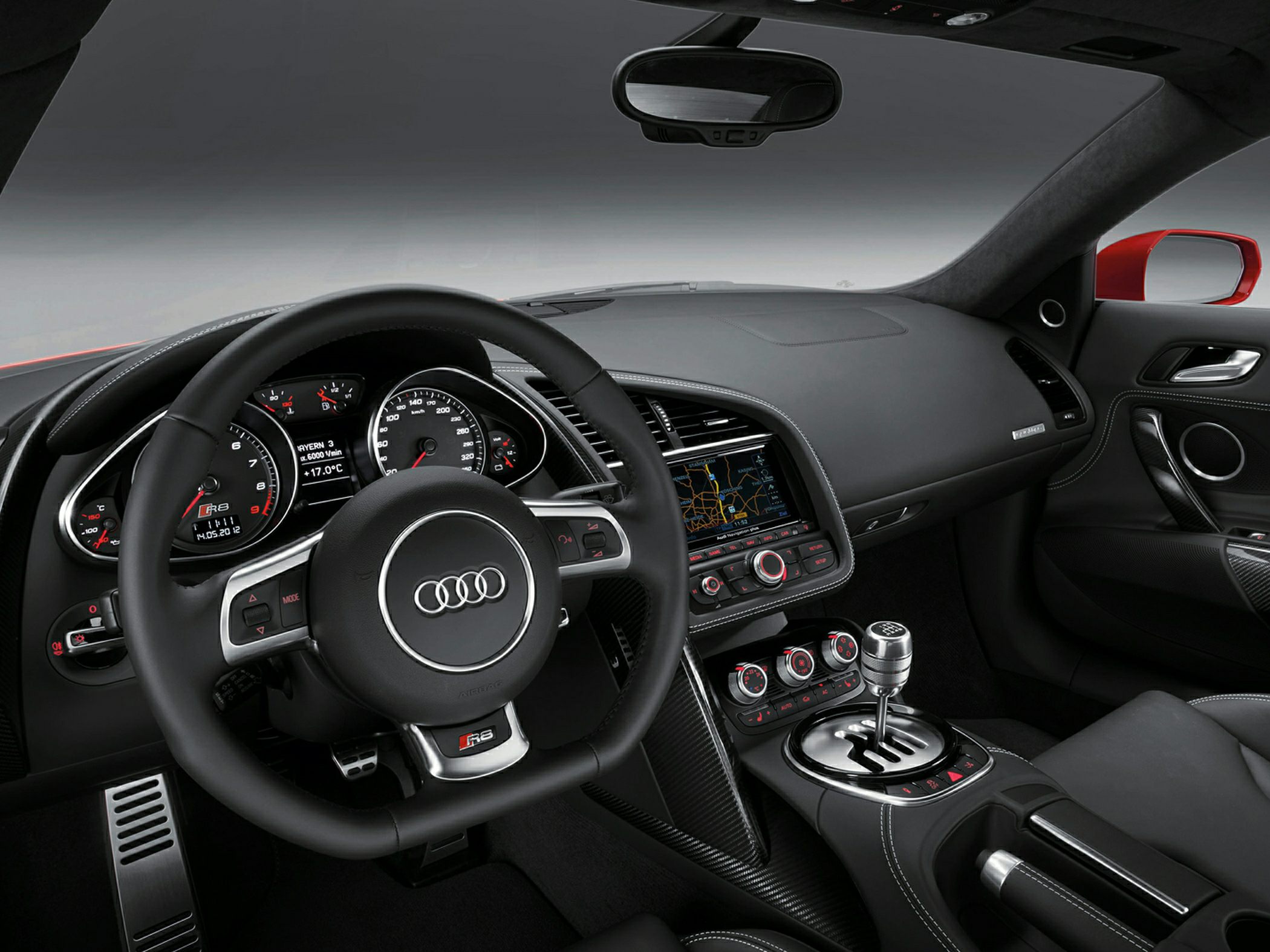 Manual gated gear stick and sports steering wheel inside a modern sports car cockpit