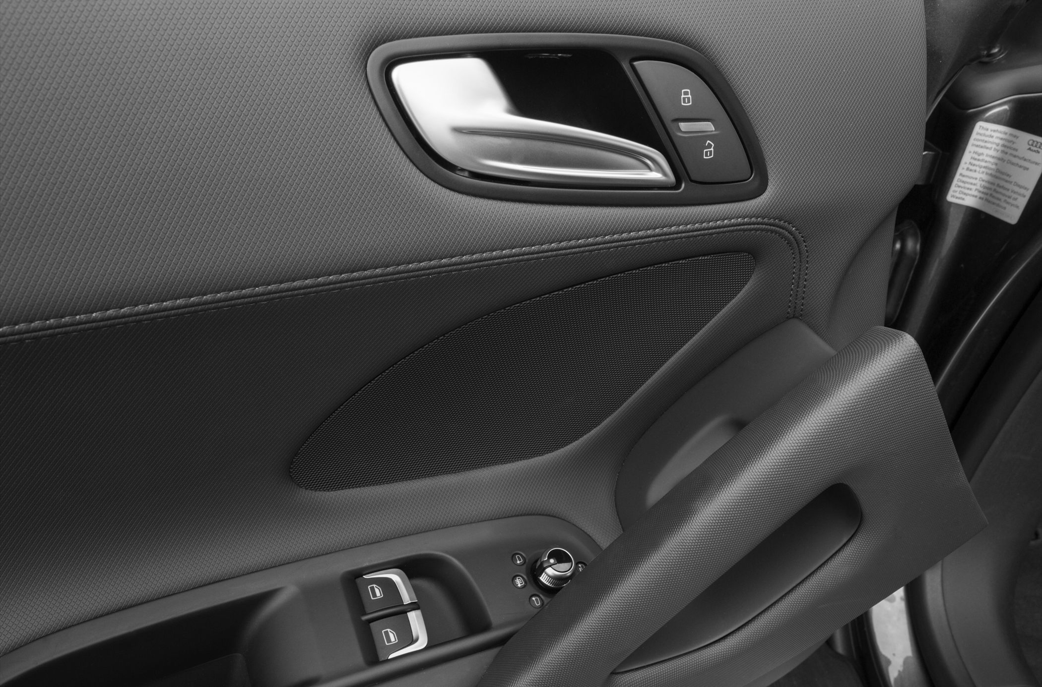 Car door interior handle, lock buttons, window controls, and textured armrest