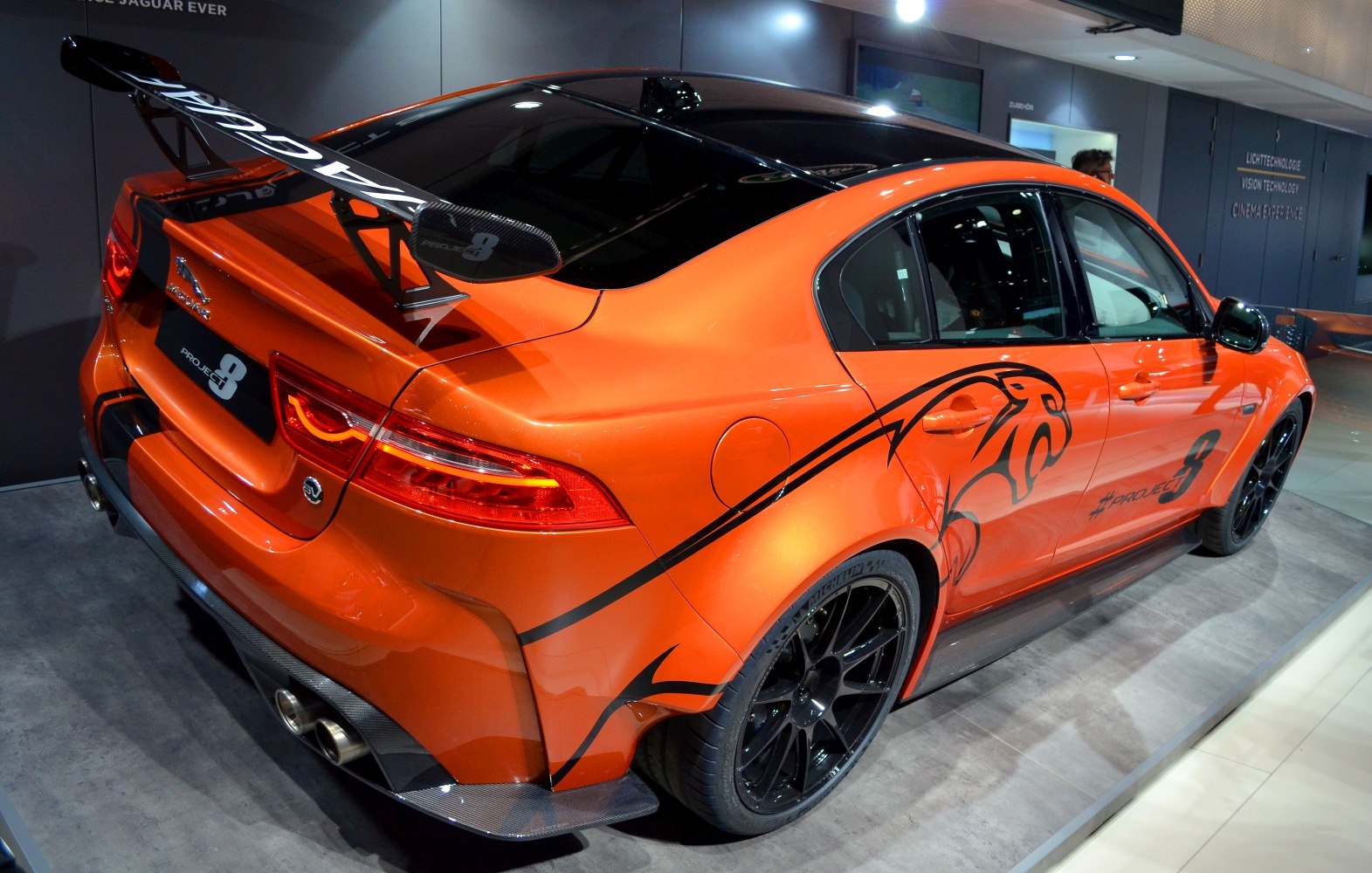 Carbon fiber rear wing and aggressive sporty decals on orange sedan