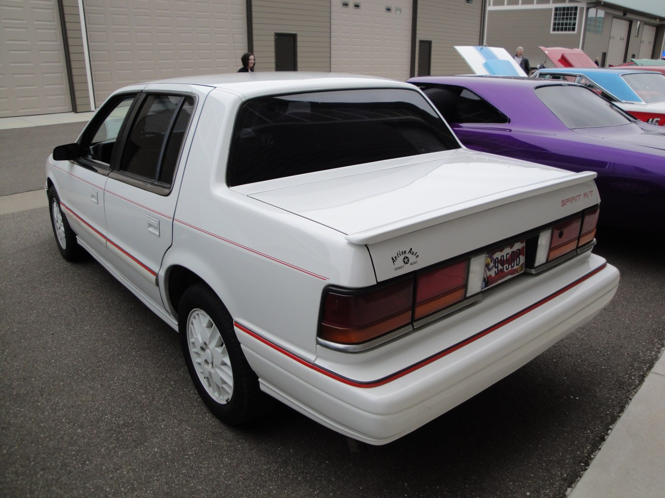 Sporty rear spoiler and red side stripe on white four-door sedan.