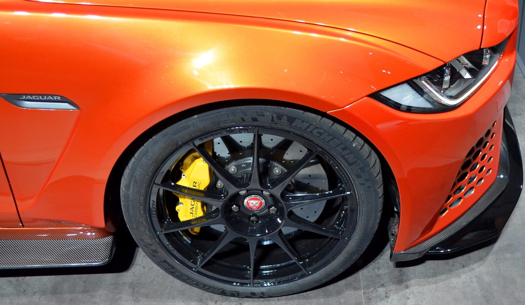 Front wheel with black alloy rim and yellow brake caliper, plus sleek front headlight