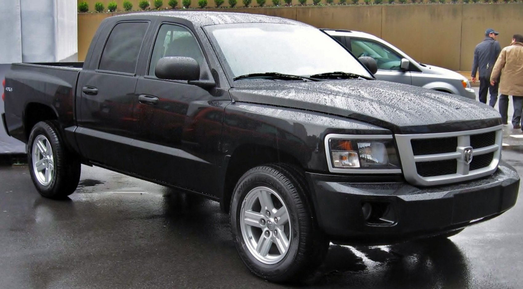 Black pickup truck front-side view with 4x4 badge and rain droplets