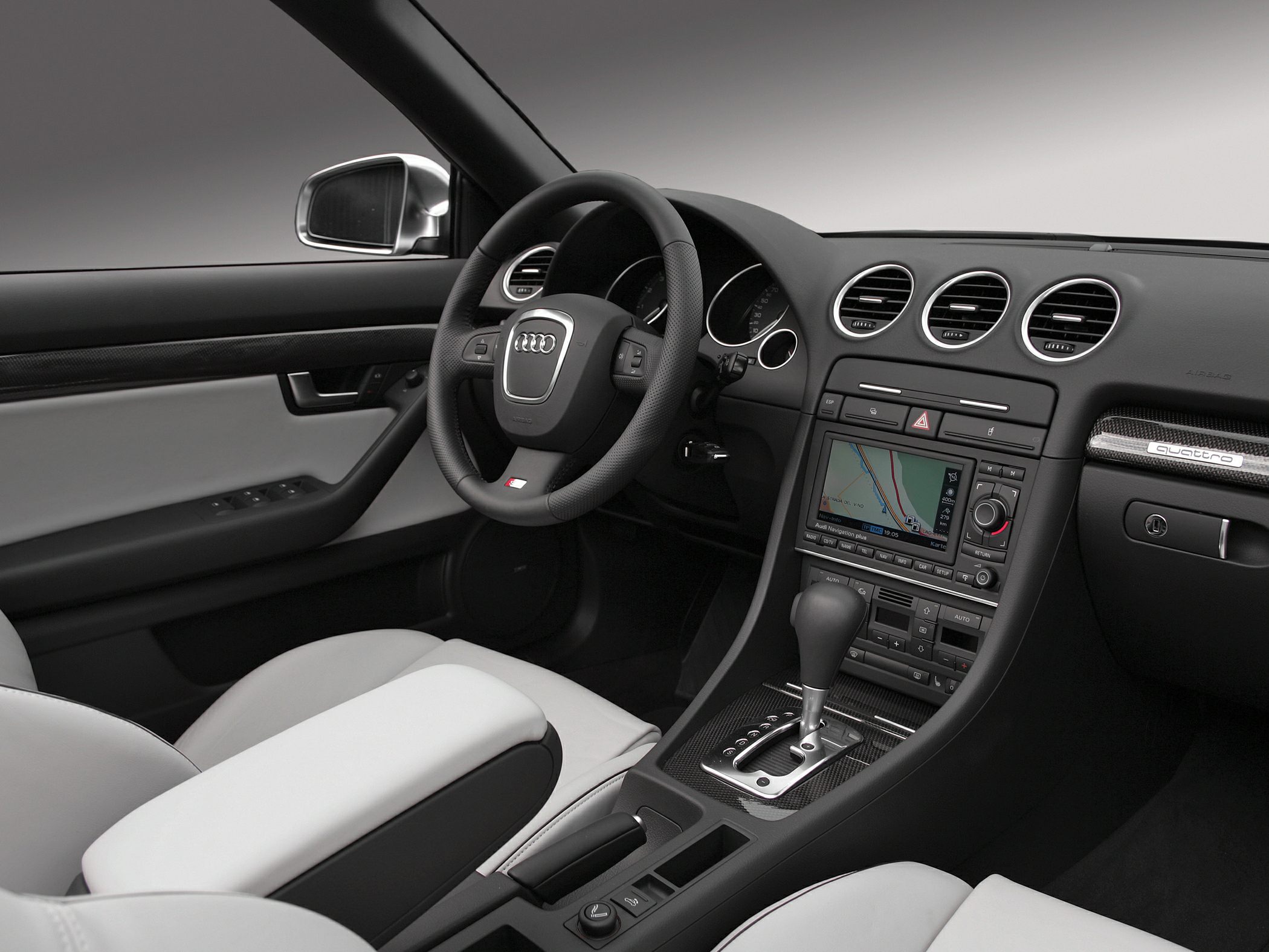Luxury car interior with dashboard, navigation screen, gear shifter, and steering wheel