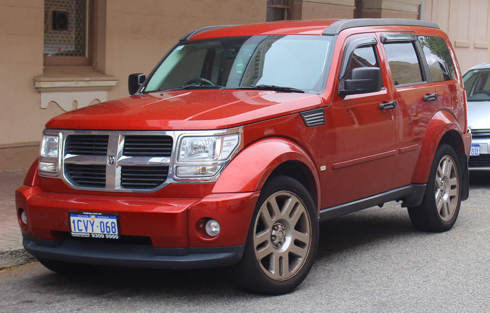 Front-side view of robust red SUV with distinctive grille and angular design