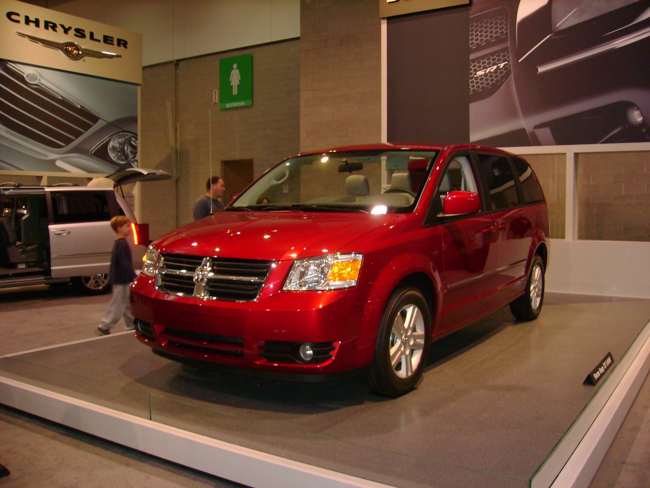 Red minivan with chrome grill and alloy wheels in showroom