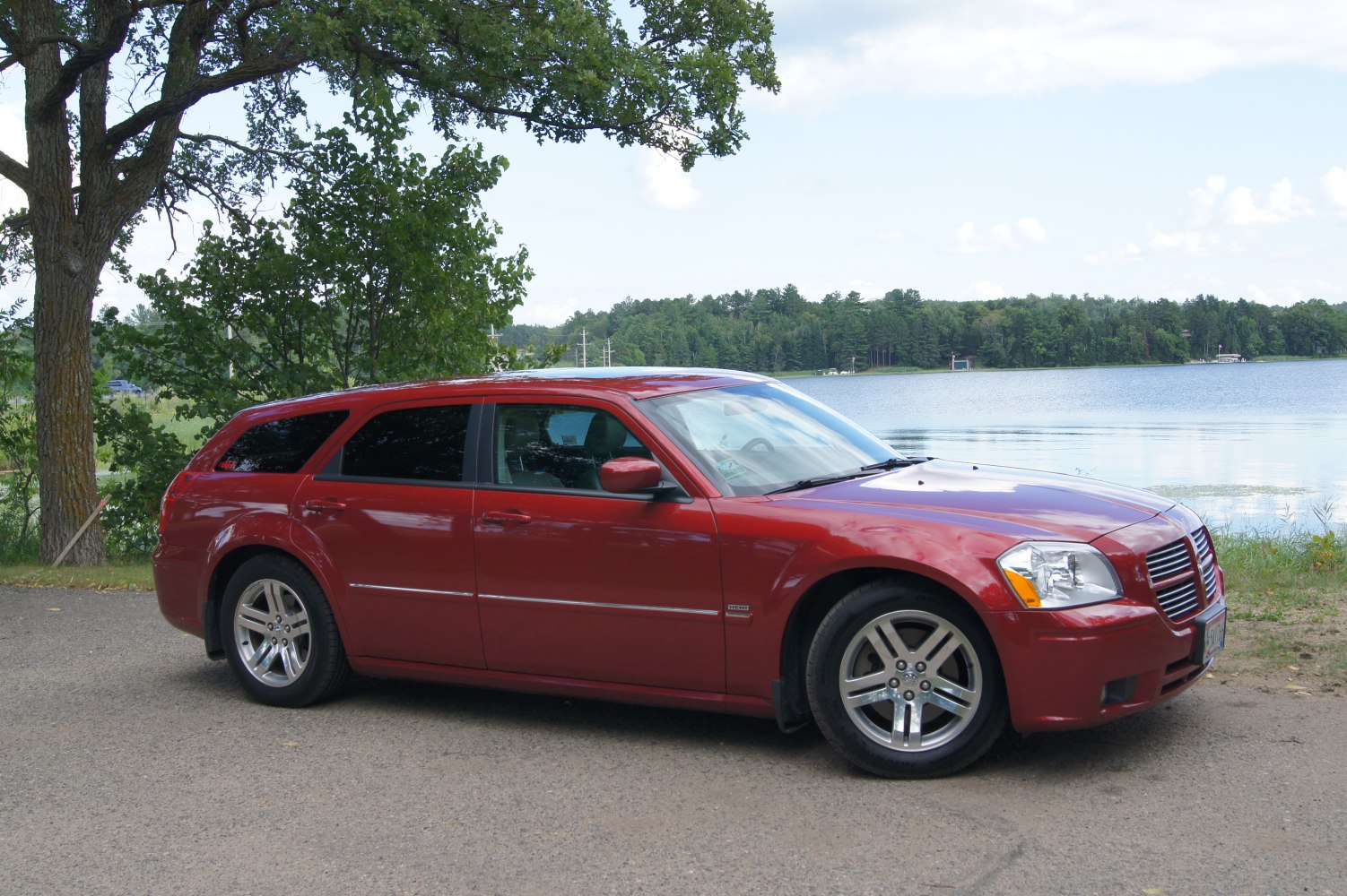 Red station wagon with alloy wheels and tinted windows parked near lake