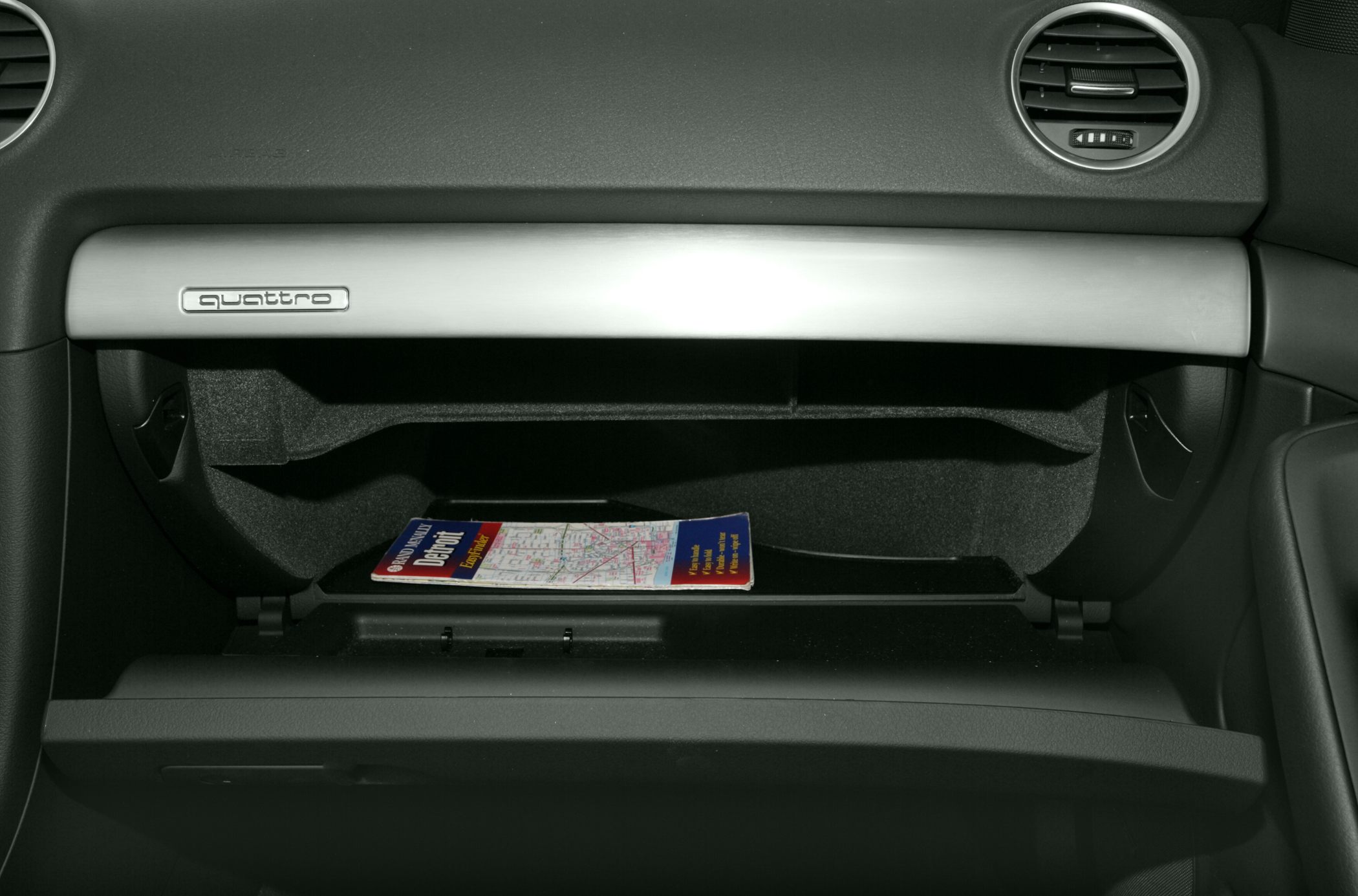 Open glove box with Quattro badge and dashboard air vent