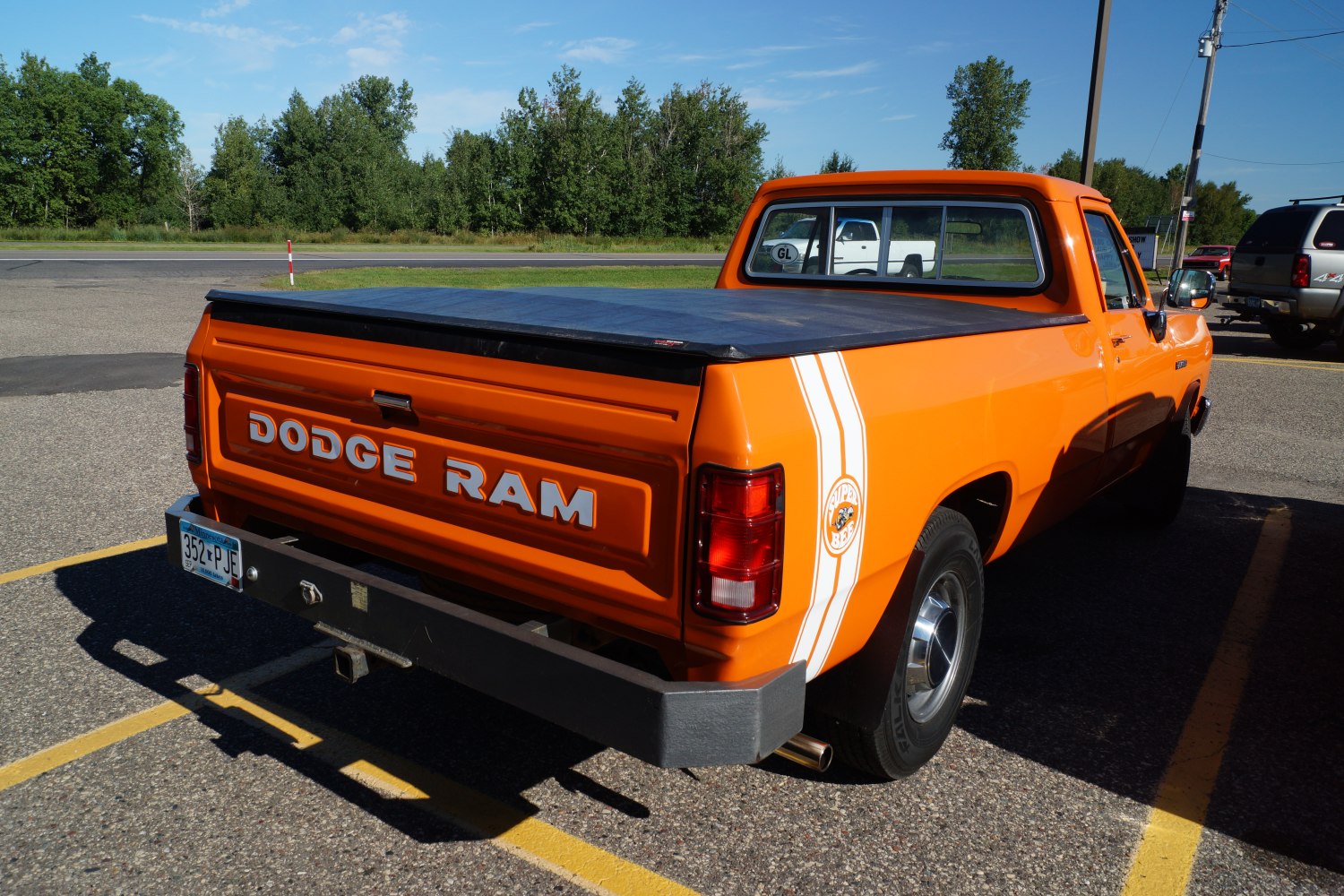 Rear view of orange pickup with Super Bee decal and bed cover