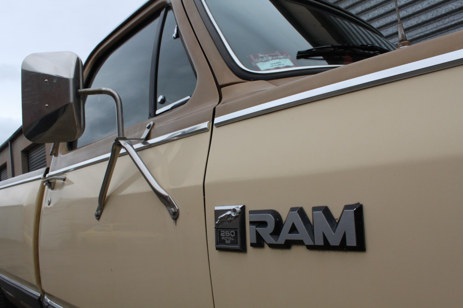 Close-up of a classic pickup truck badge and side mirror.