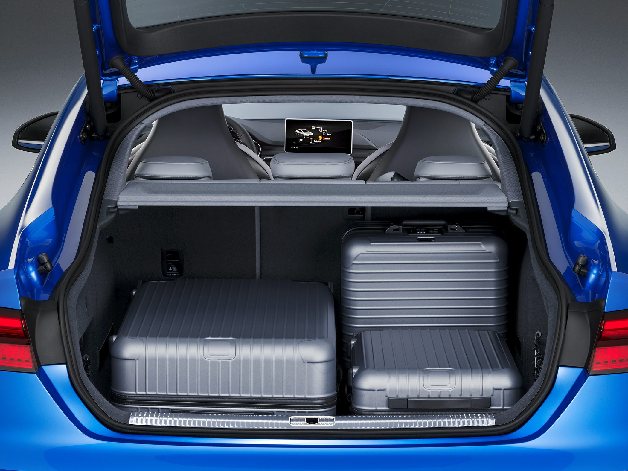 Trunk space with three silver suitcases and retractable cover