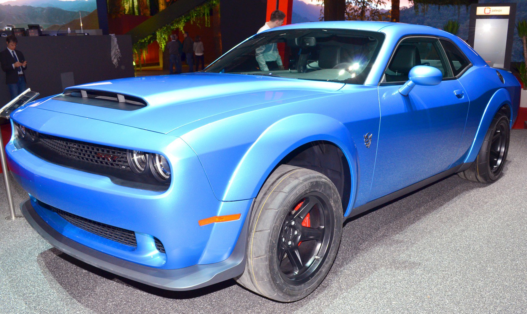 Blue muscle coupe with hood scoop and wide black rims on performance tires